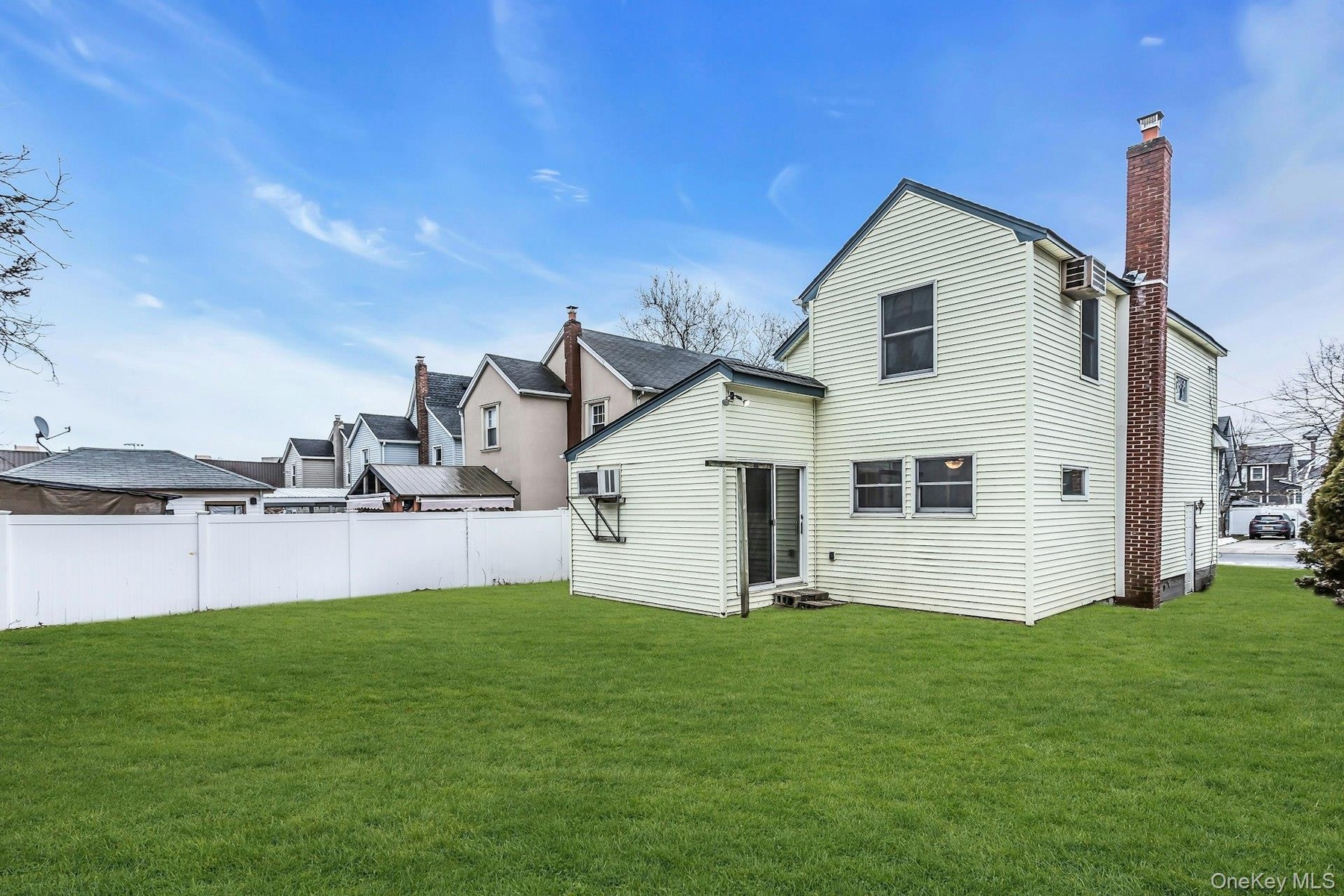 Expansive green lawn with a white privacy fence