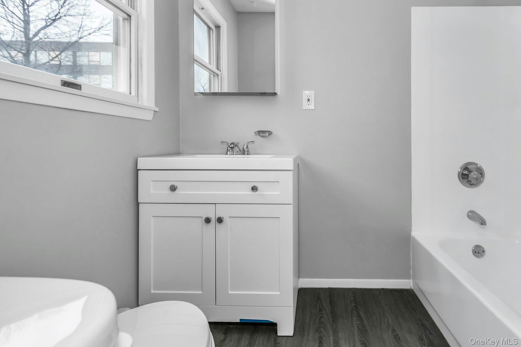 Bathroom featuring a white vanity with integrated sink, chrome faucet, and mirrored medicine cabinet