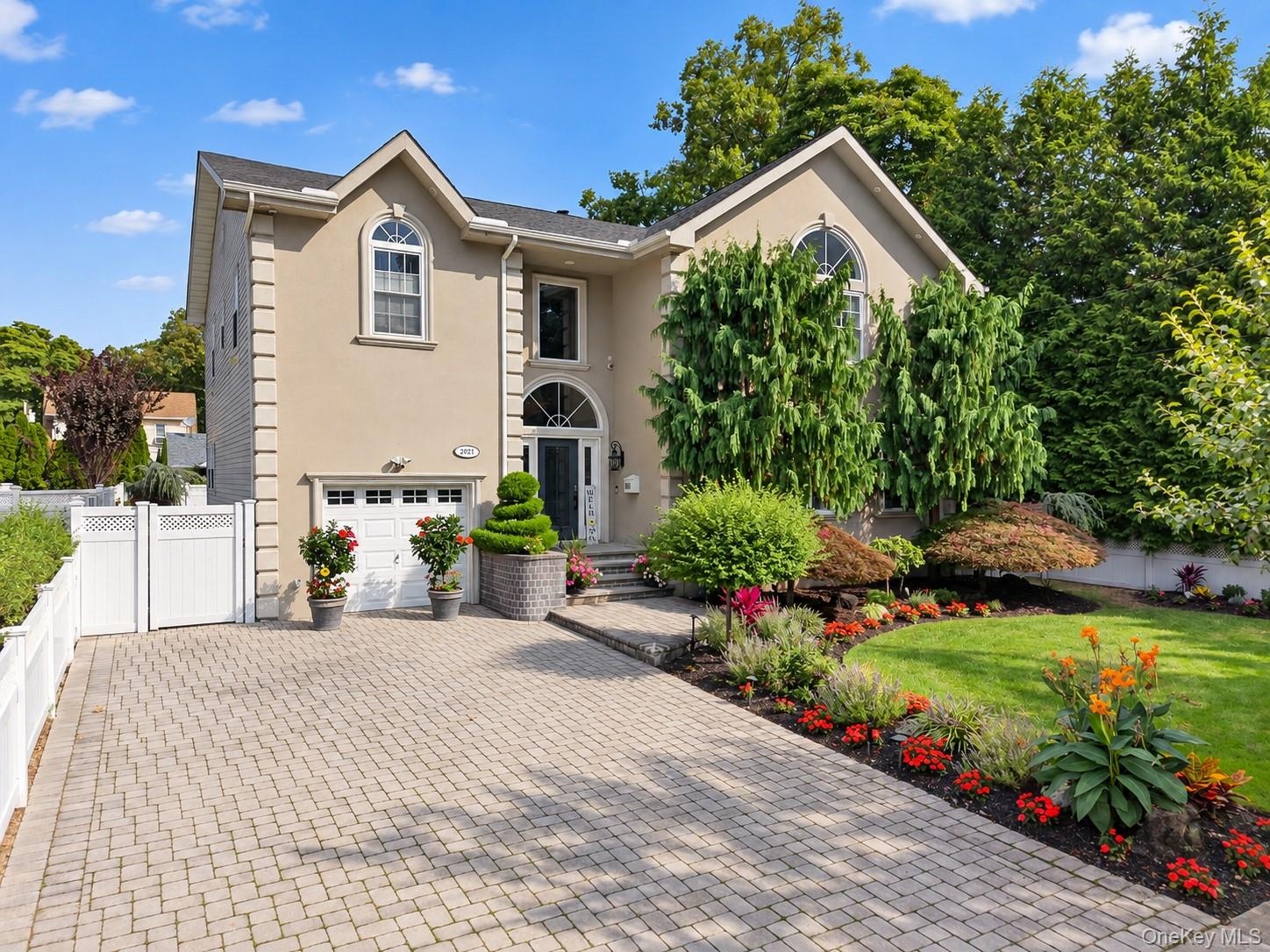 Stucco exterior with an arched entryway, integrated garage, and a paver driveway