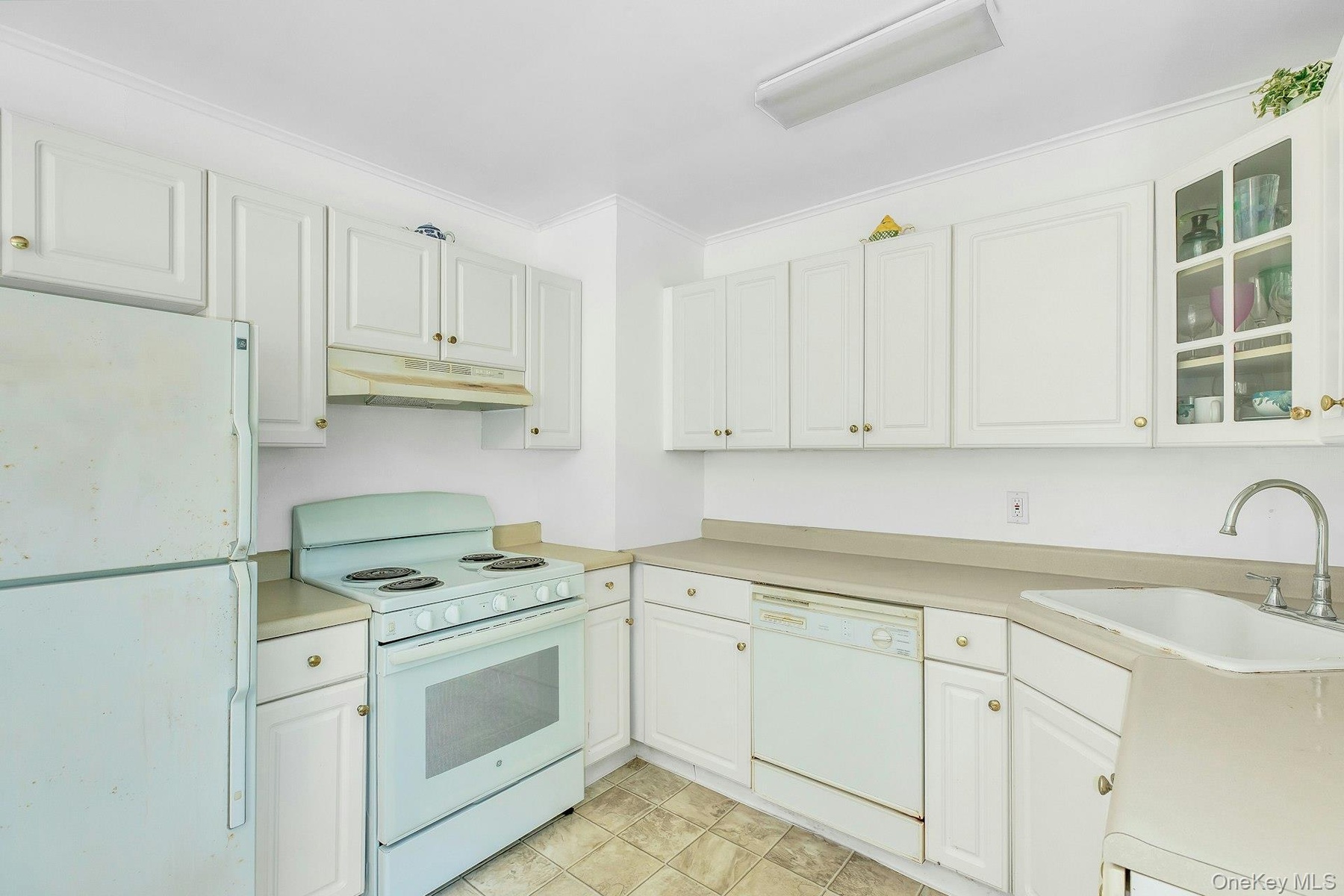 Kitchen featuring white cabinetry, light-toned countertops, tile flooring, a white range, and a white refrigerator