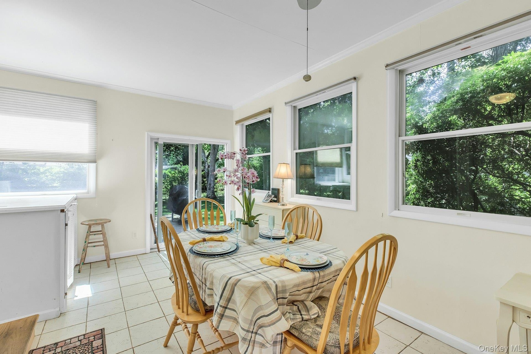 Tile flooring, multiple windows, sliding glass door, crown molding, and a pendant light fixture