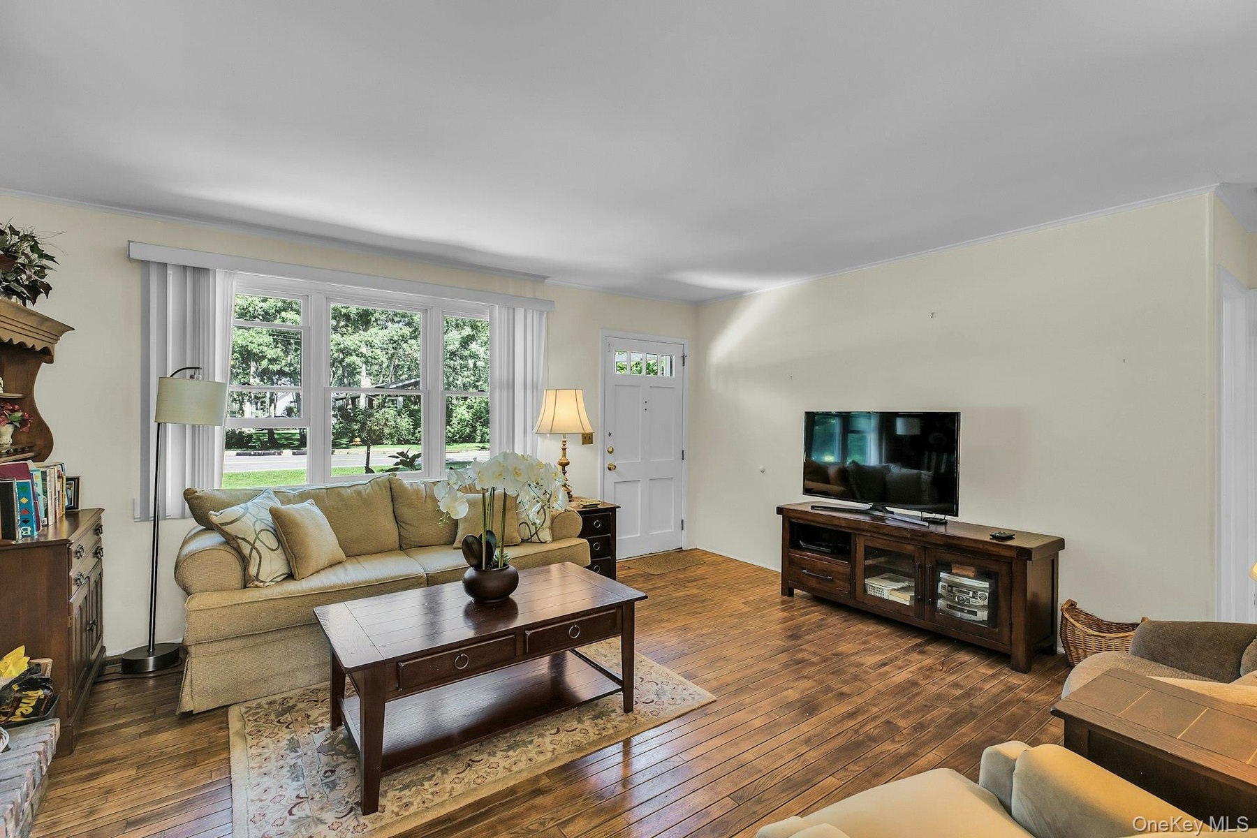 Light-toned wall finishes, wide plank wood-finish flooring, and a multi-pane window