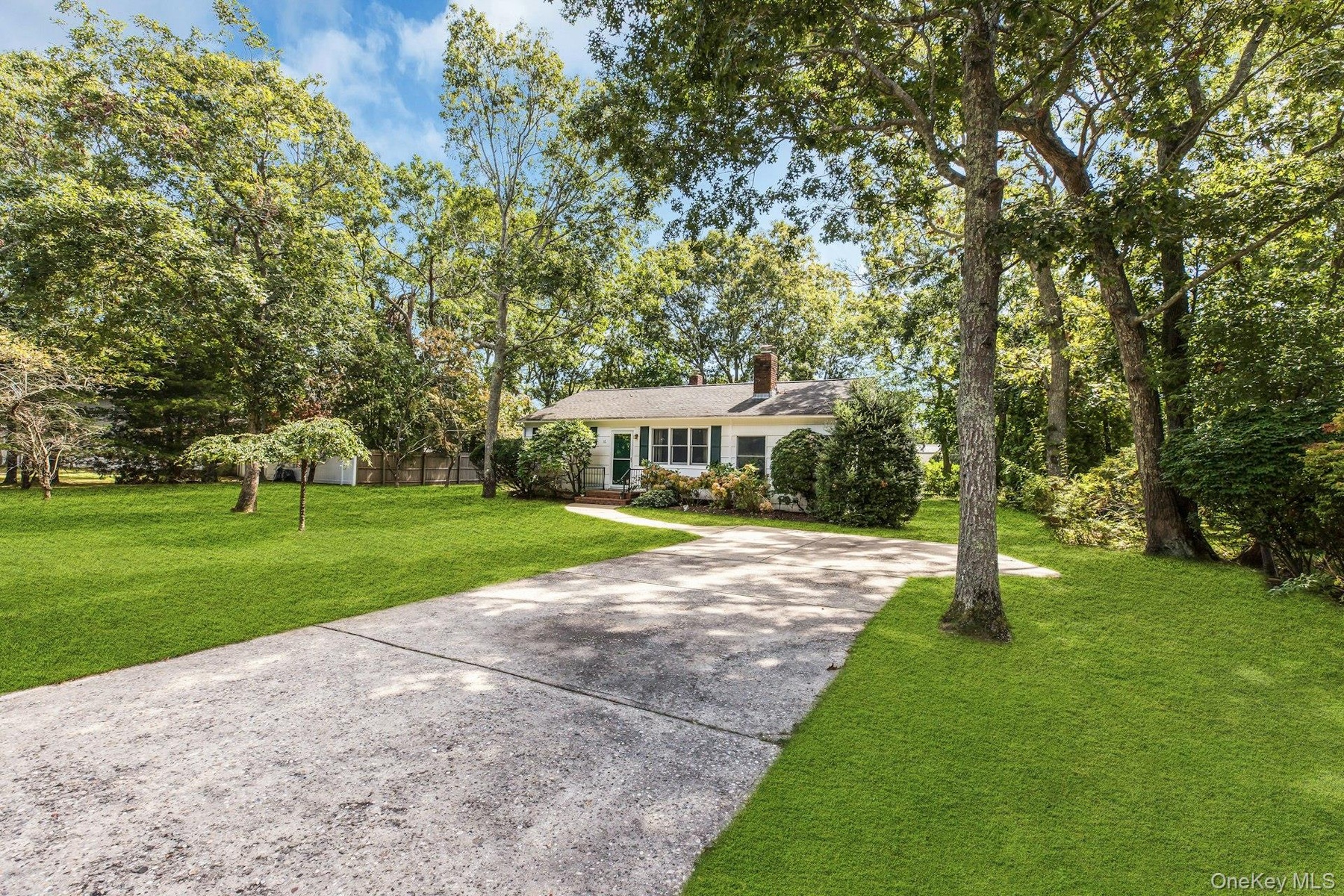 Mature landscaping with towering shade trees frames this single-story residence, set on expansive grounds with a manicured lawn