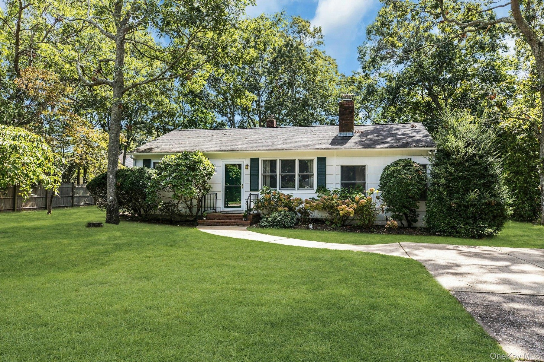 Ranch-style exterior with white siding, dark green shutters, and a gray shingle roof