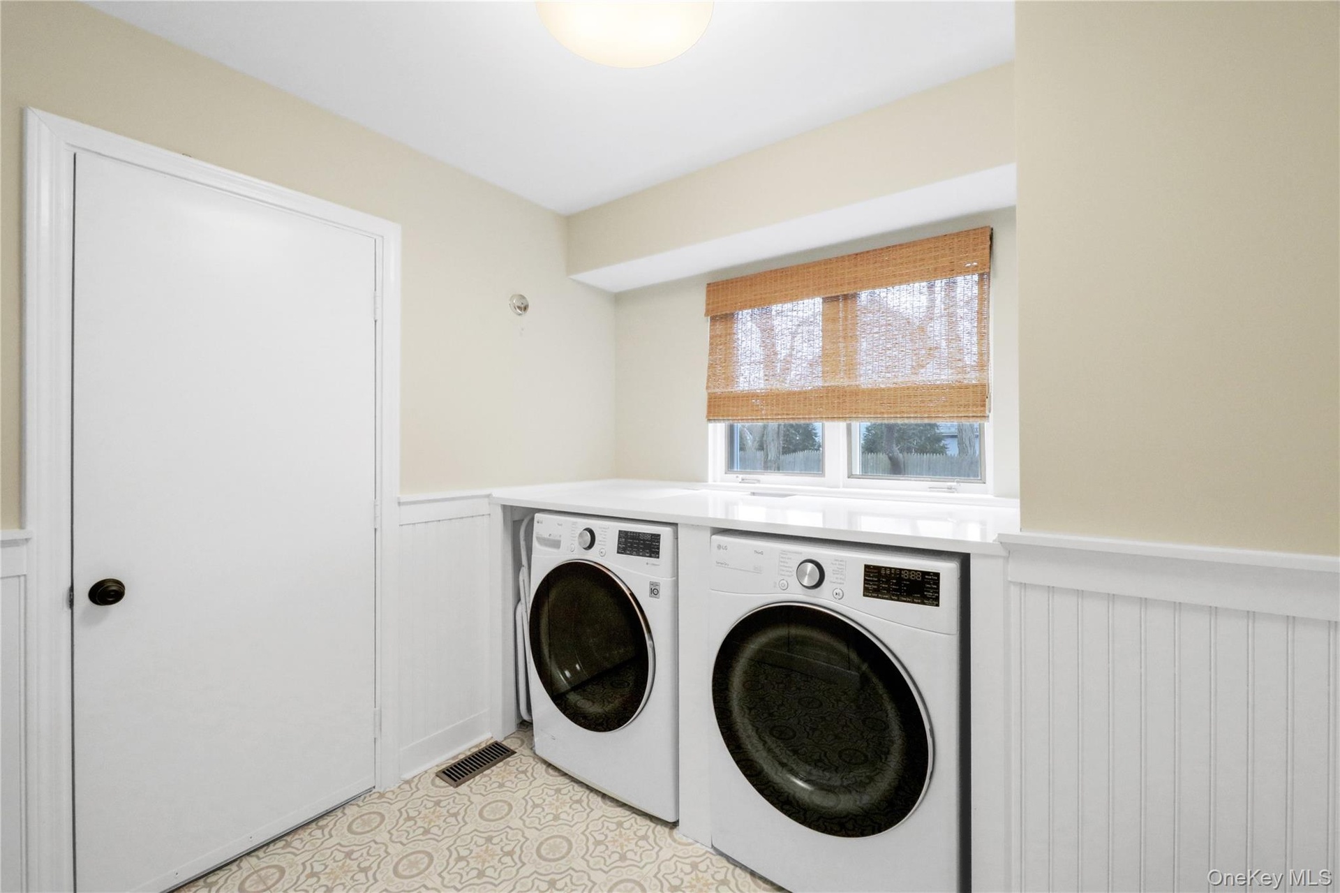 Laundry room featuring wainscoting, independent washer and dryer, and a decorative wall
