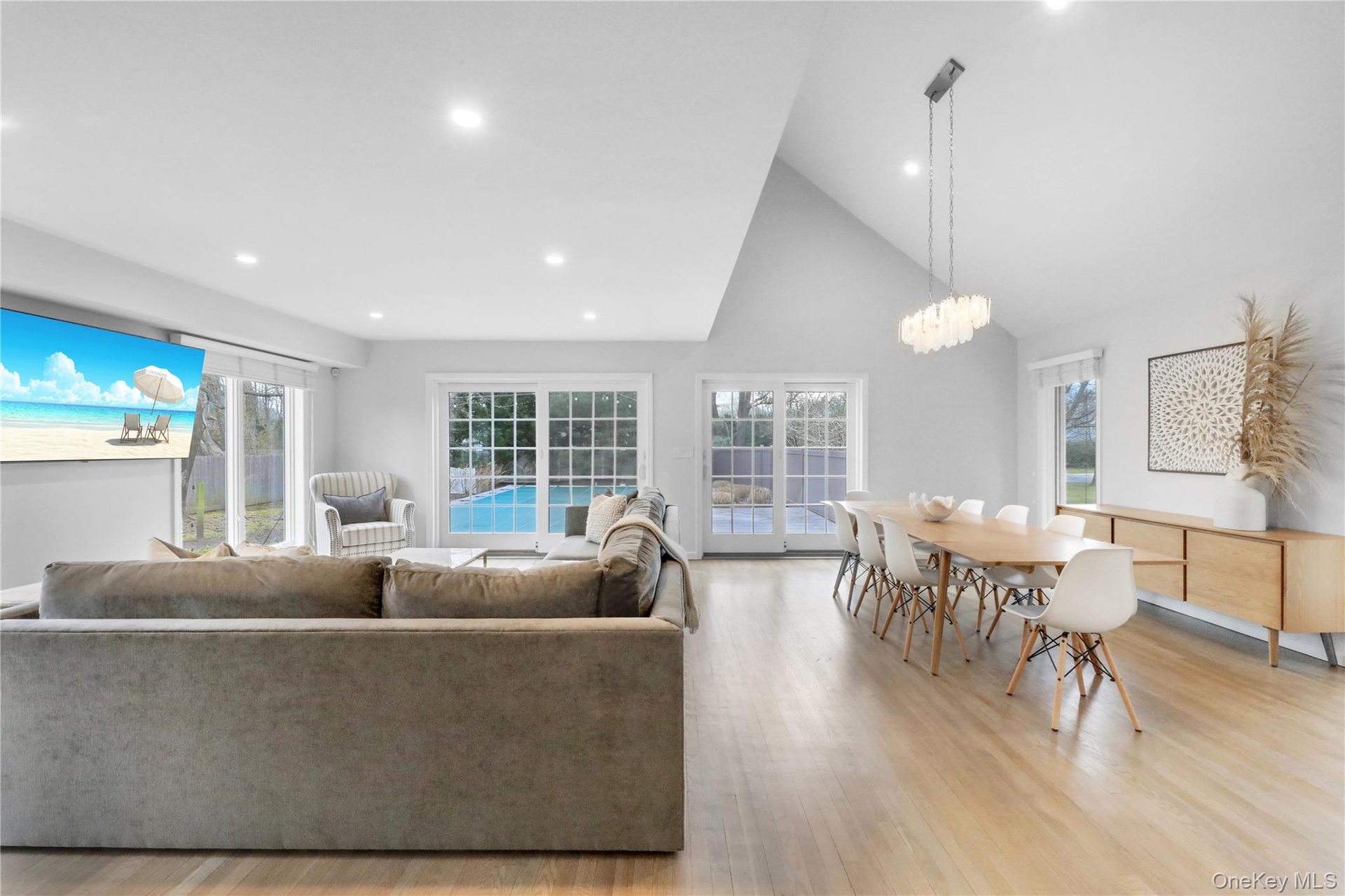 Living room featuring high vaulted ceiling, healthy amount of natural light, recessed lighting, light wood-style flooring, and a chandelier