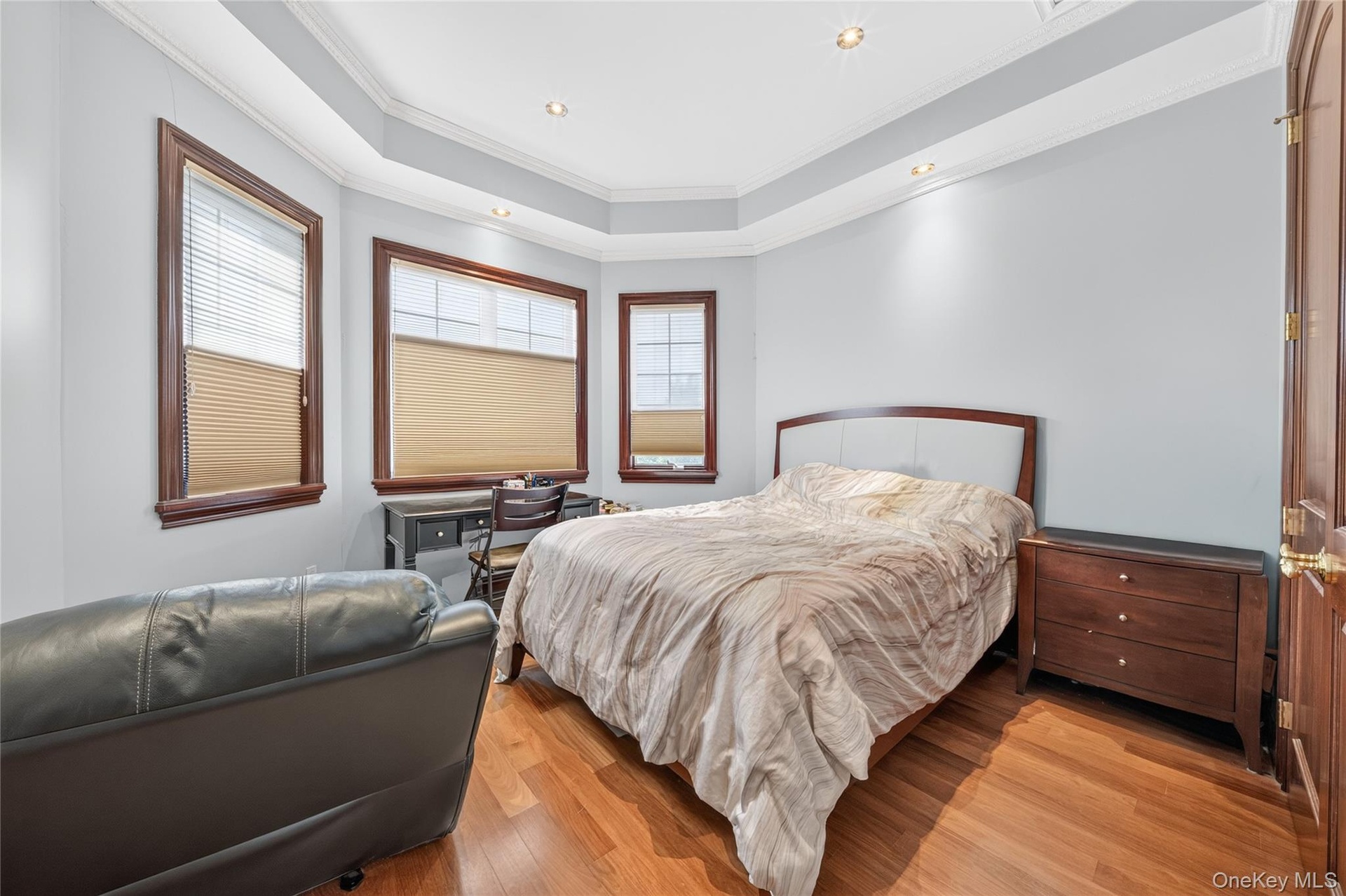 Hardwood flooring, tray ceiling with recessed lighting, multiple windows with wood trim, interior wood door