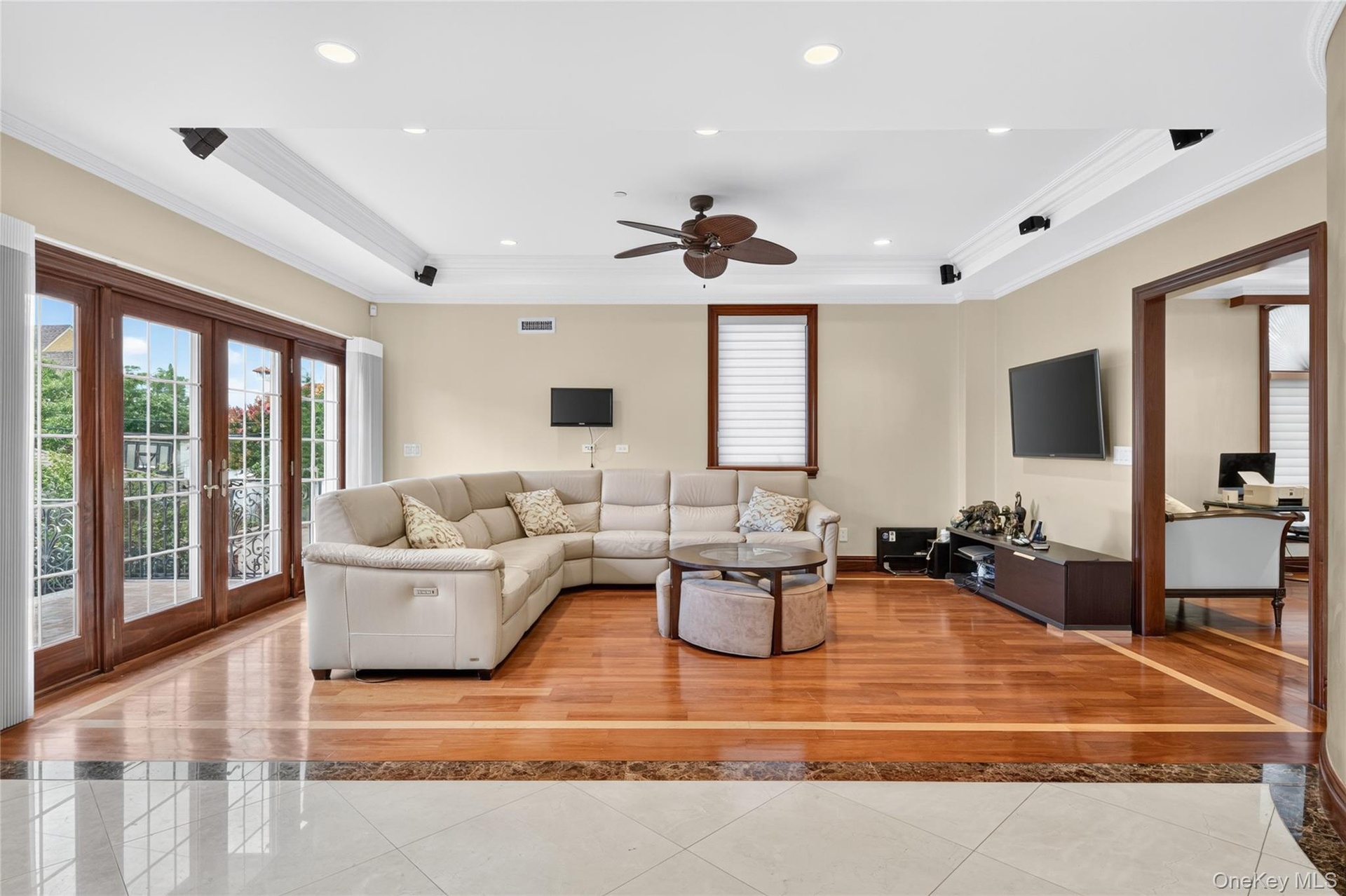 Hardwood flooring with a marble border, recessed lighting, crown molding, double French doors, and a ceiling fan