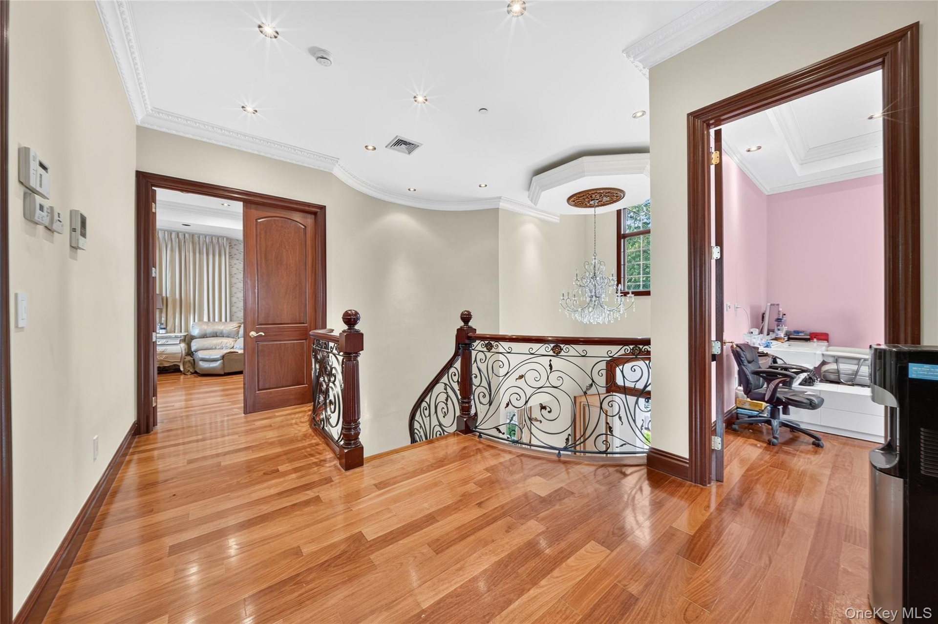 Hardwood flooring throughout, crown molding, recessed lighting, and ornate wrought iron railing