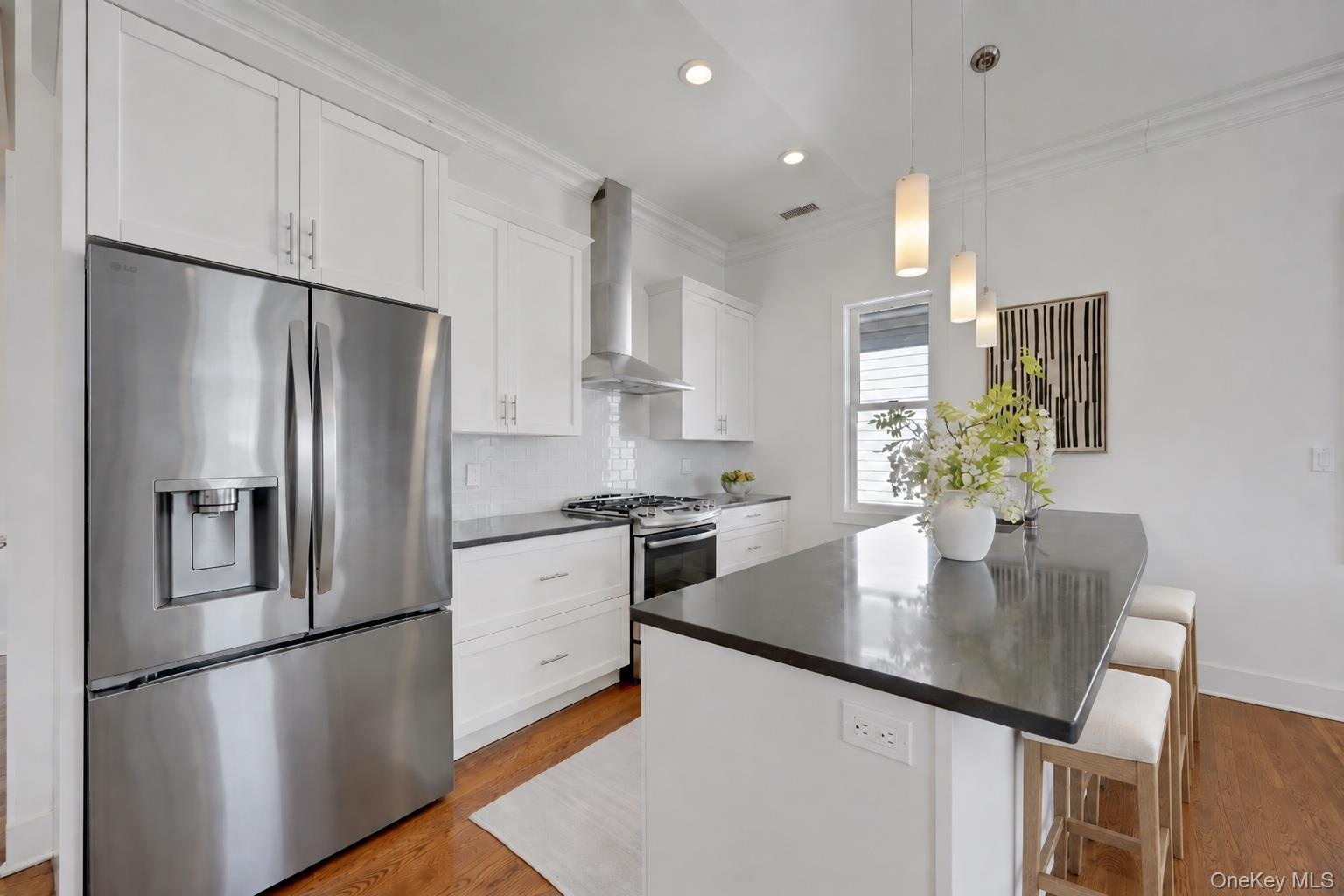 Modern kitchen with white maple wood cabinetry, glass tile backsplash and stainless appliances.