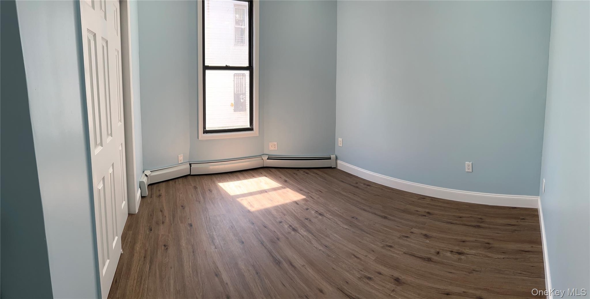 Bedroom#1 first floor featuring wood-finish flooring, light blue walls, and a multi-pane window