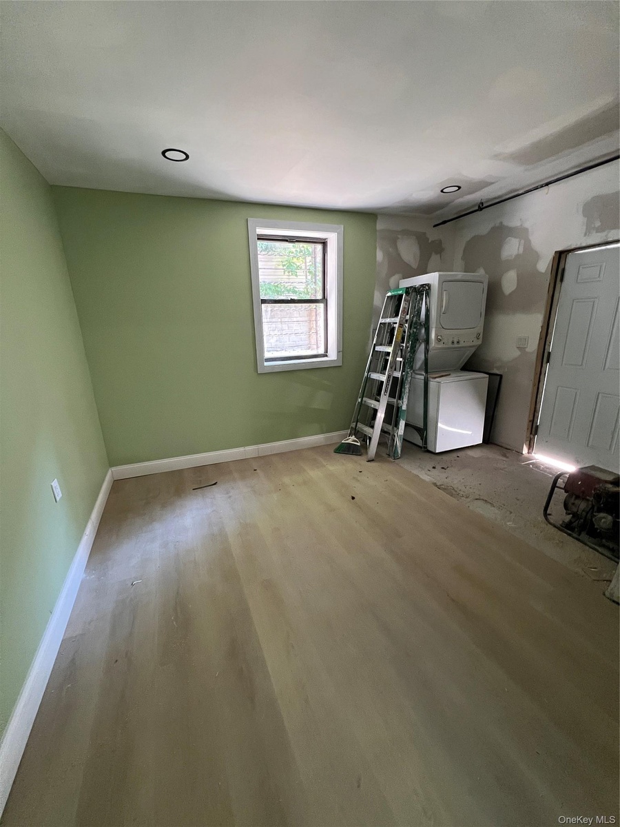 back basement Room featuring light wood finish flooring, recessed lighting, and a single window with white trim
