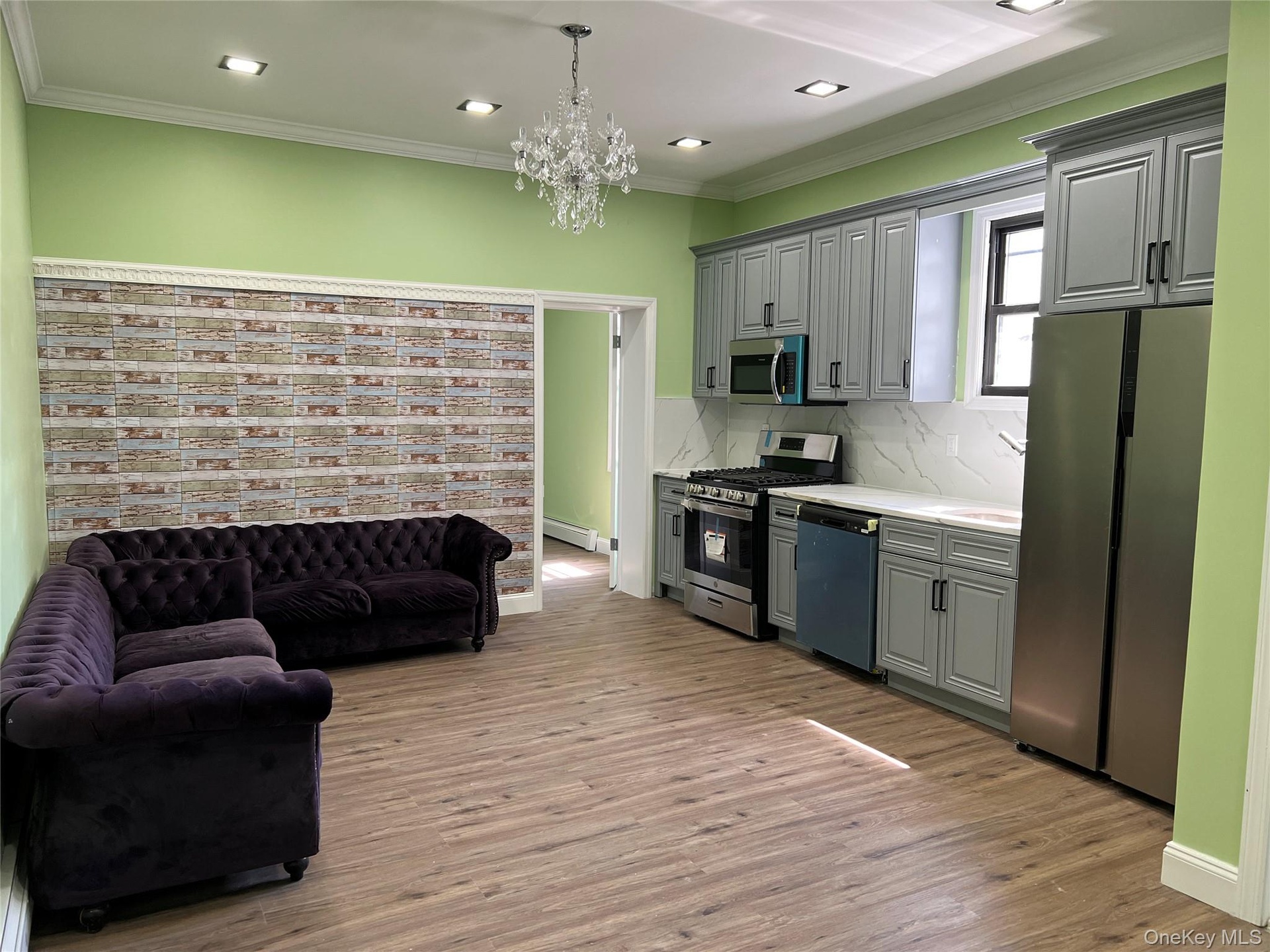 Open-concept living space featuring wood-finish flooring, recessed lighting, and a crystal chandelier