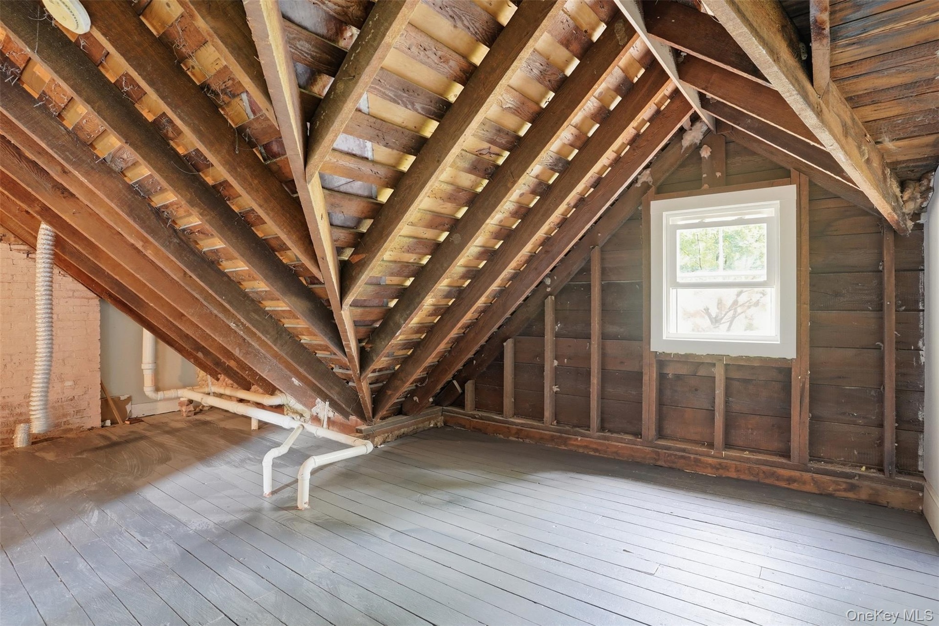 Exposed wood rafters, painted wood flooring, and a white-framed window