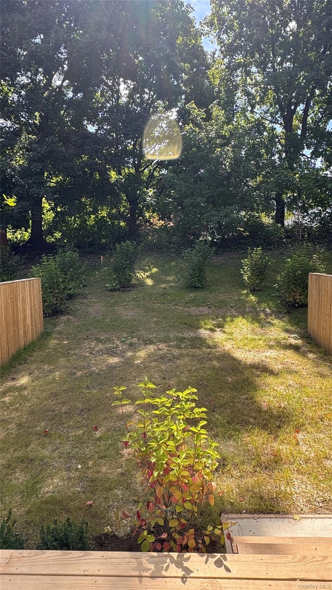 Expansive backyard featuring a grass lawn, mature trees, and privacy fencing