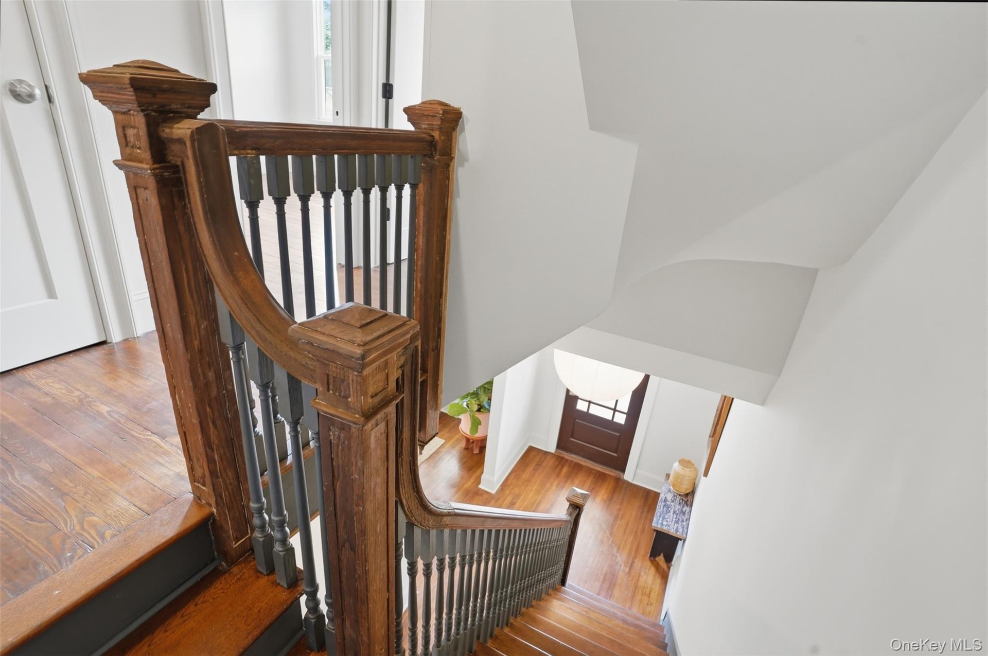 Hardwood flooring, wood newel posts, and dark balusters accent the staircase