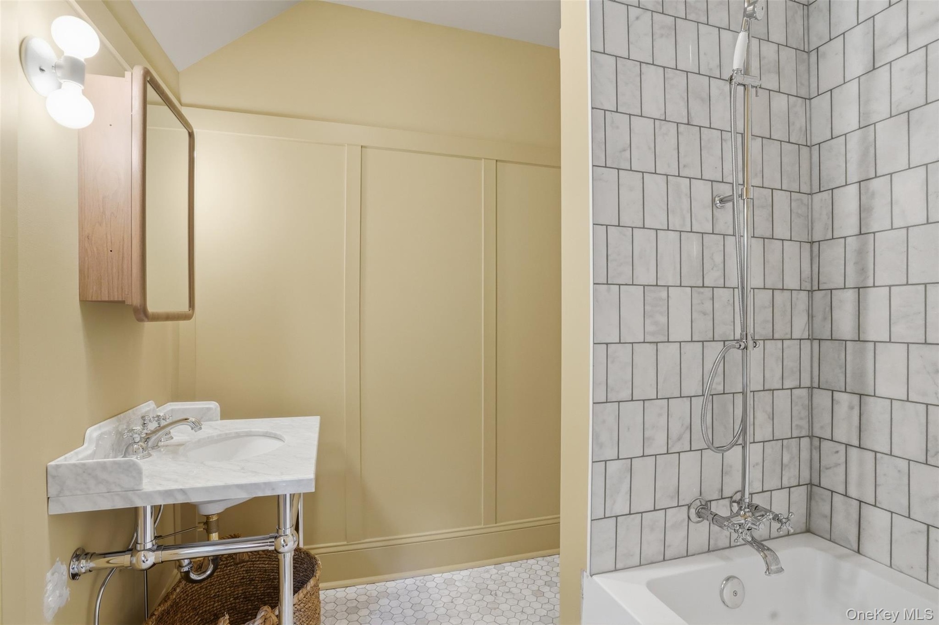 Corner vanity with a marble top, chrome fixtures, and wood-finish medicine cabinet