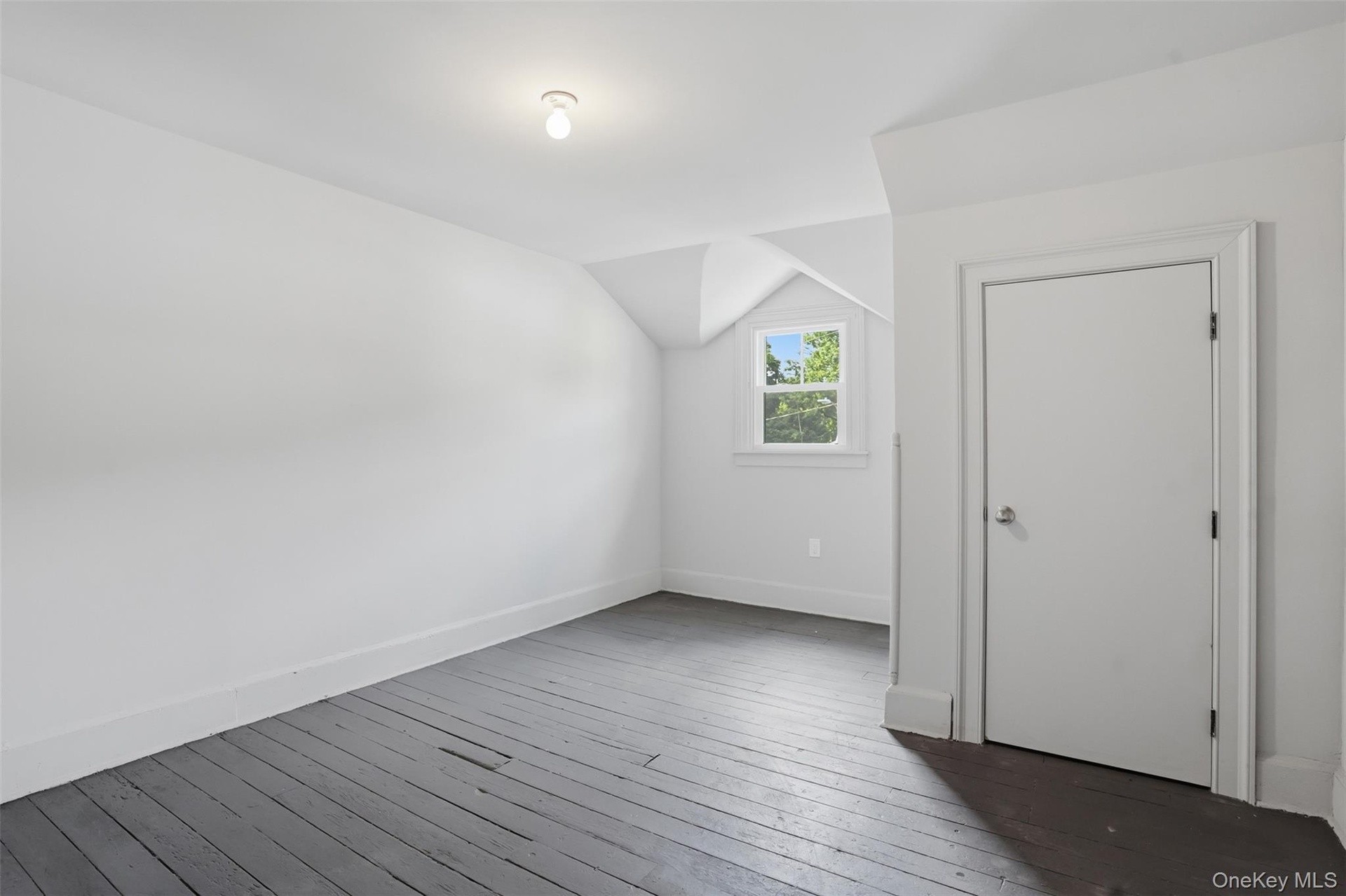 Painted wood flooring, white walls, angled ceiling, single window, interior door