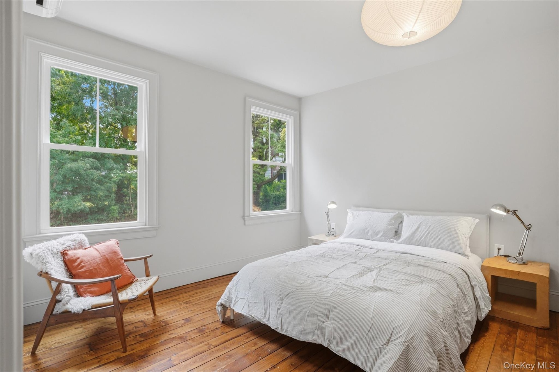 Hardwood flooring, white walls, two single-hung windows, and a flush mount ceiling light fixture