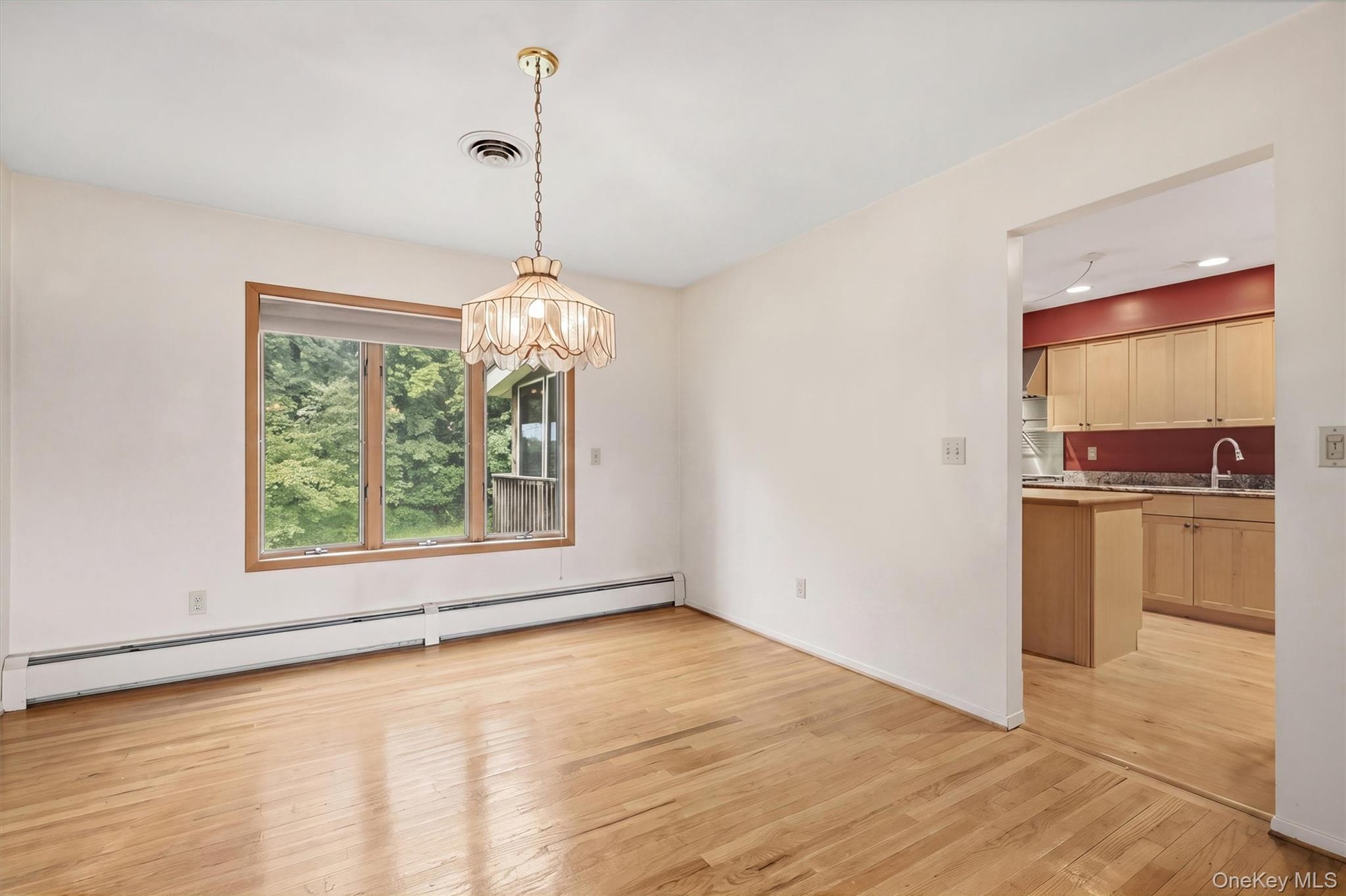 Hardwood flooring, natural wood window trim, pendant light fixture, and baseboard heating
