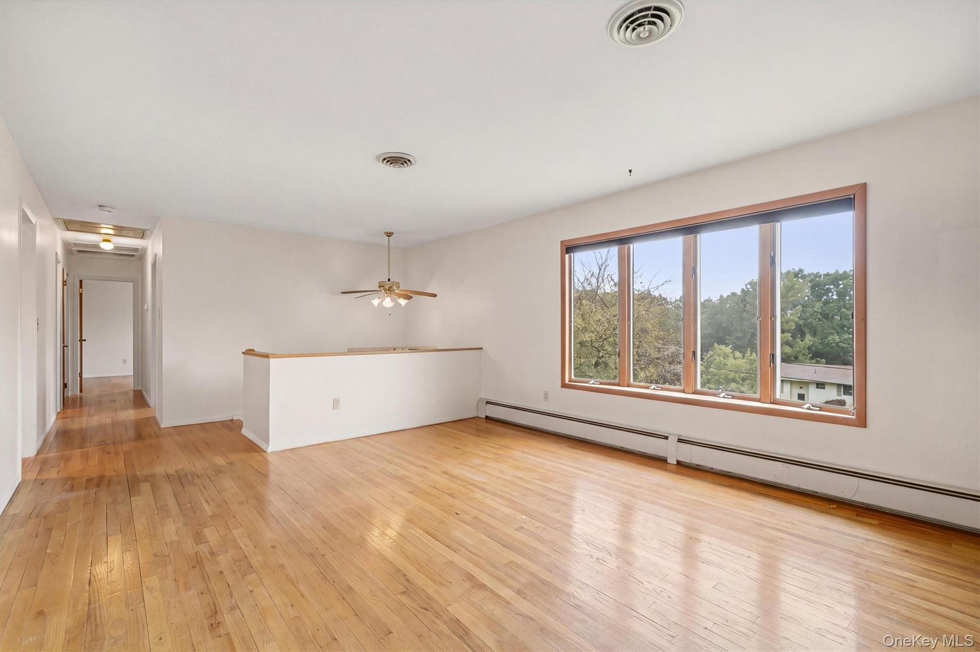 Expansive interior space featuring wood flooring, a multi-pane window with wood-finish trim,