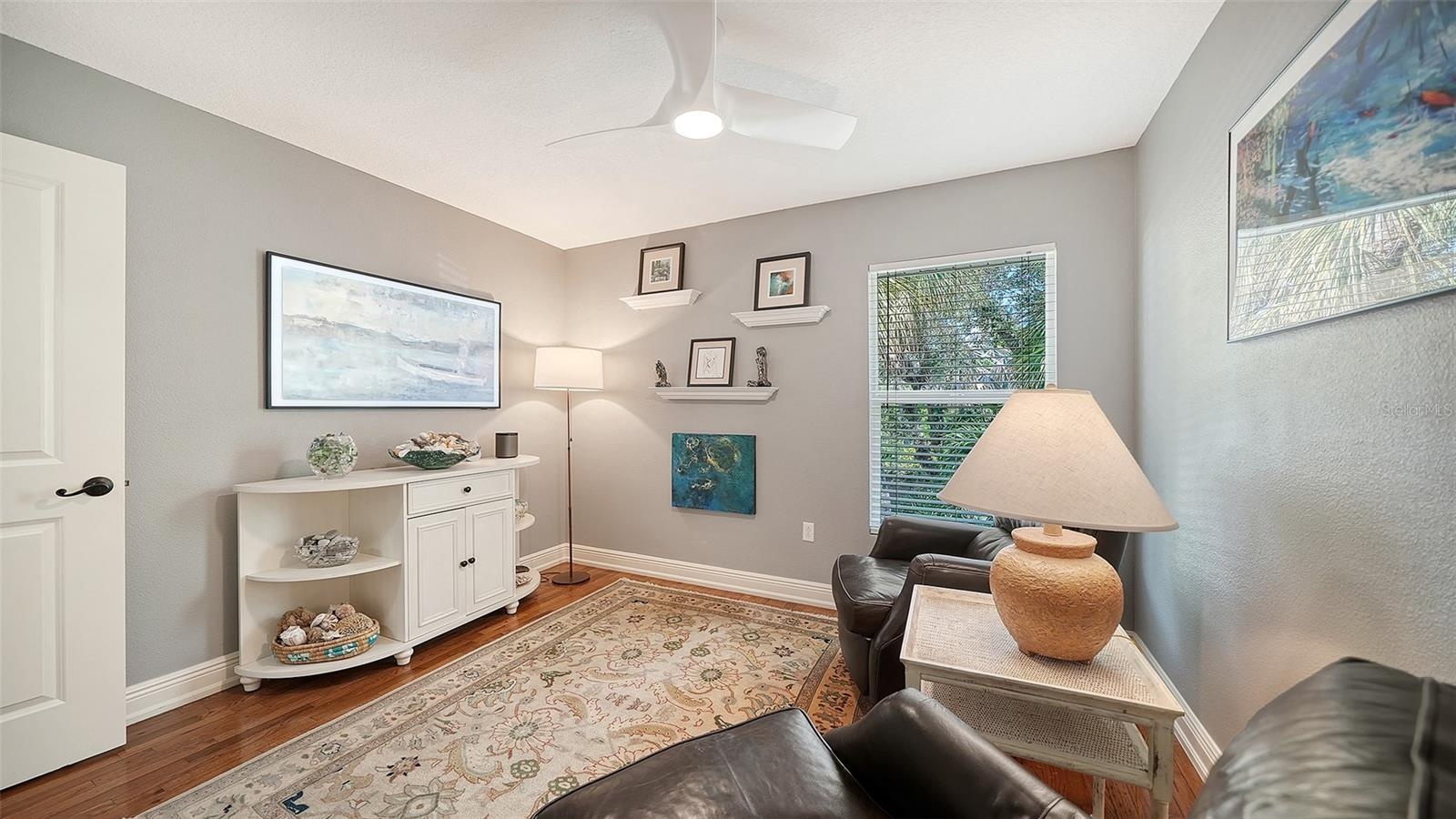 Bright guest bedroom or flexible space with hardwood flooring.