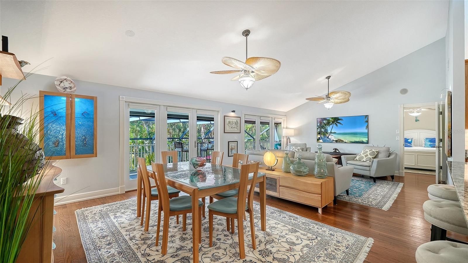 Open concept dining and living areas with hardwood floors and vaulted ceilings.