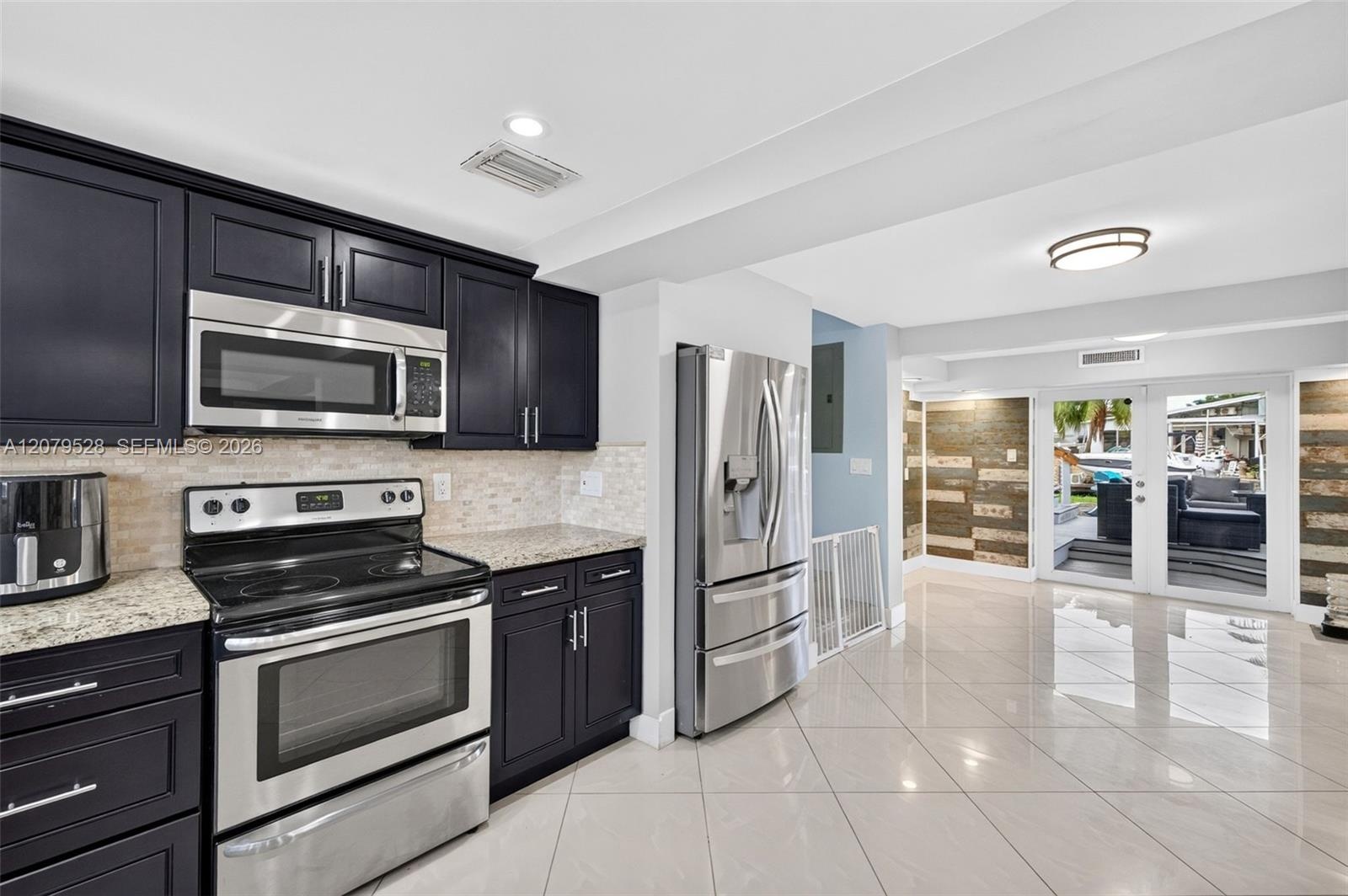 Large bright kitchen w/ windows everywhere, plantation shutters, wood cabinets, stainless appliances and granite counters