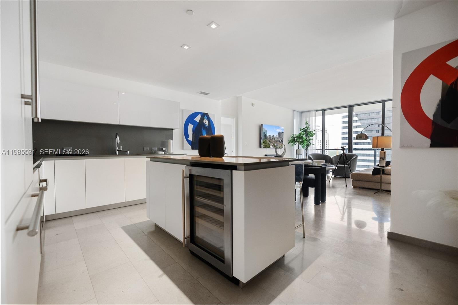 Kitchen featuring flat-panel white cabinetry, grey solid-surface countertops, seamless grey backsplash, stainless steel microwave, and integrated cook