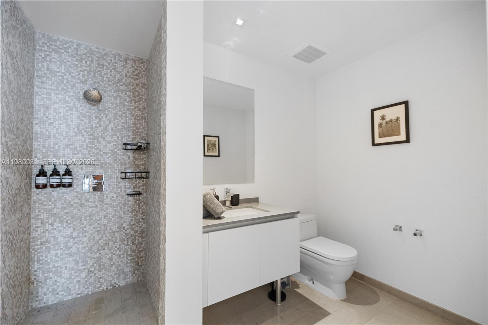 Elevated balcony with a glass railing overlooking an urban cityscape featuring high-rise buildings and transit infrastructure