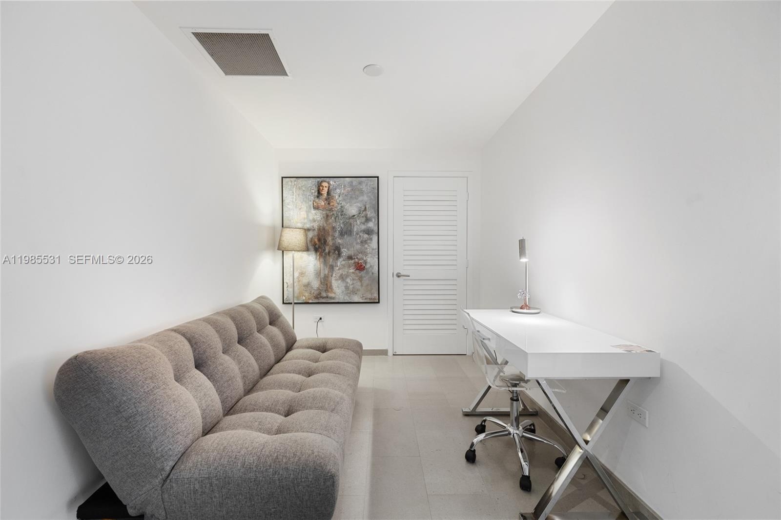 Stacked white laundry appliance set housed in a dedicated closet featuring a louvered door