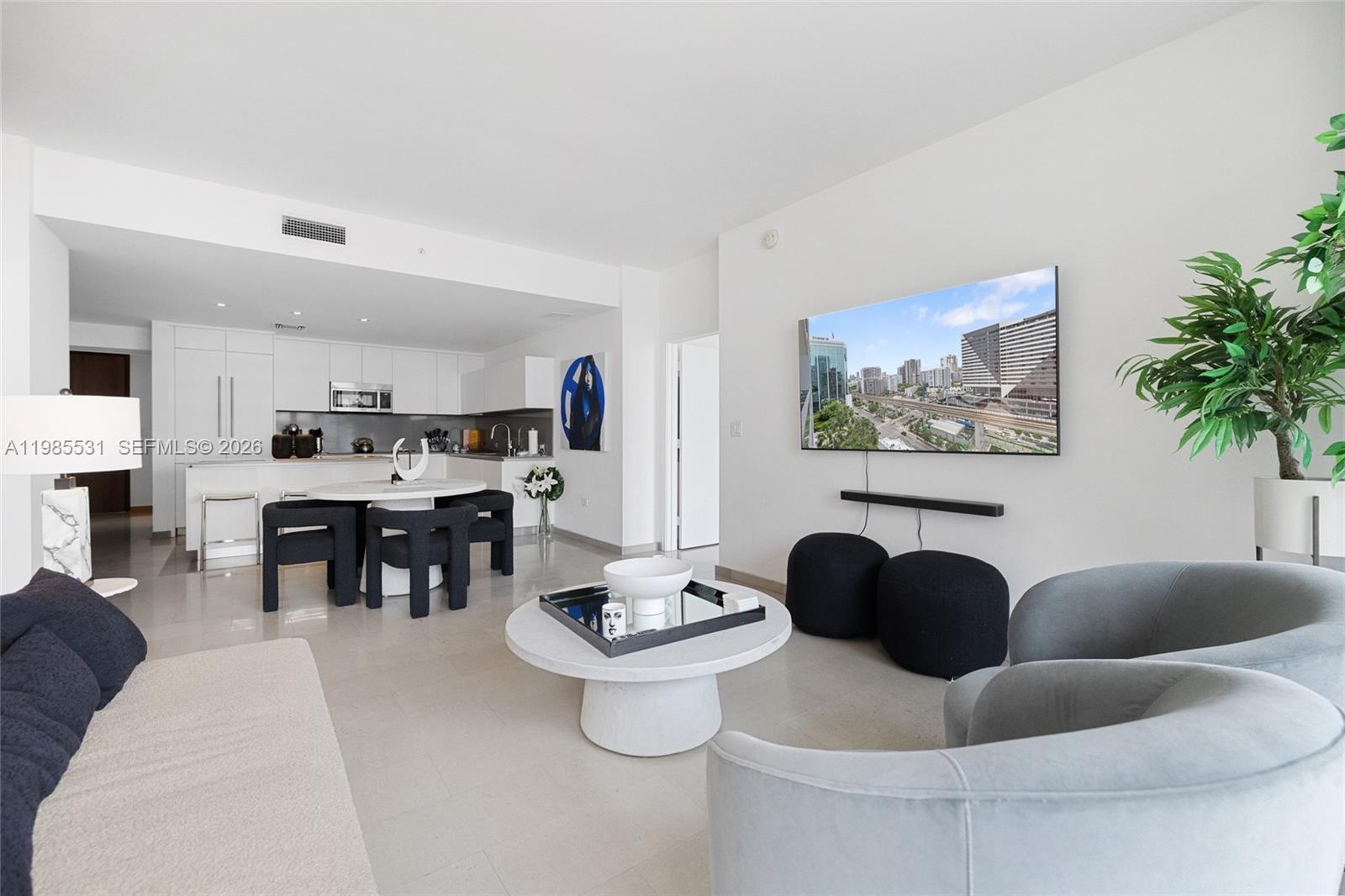 Open-concept living space featuring high-gloss white cabinetry, stone-finish flooring, and floor-to-ceiling windows