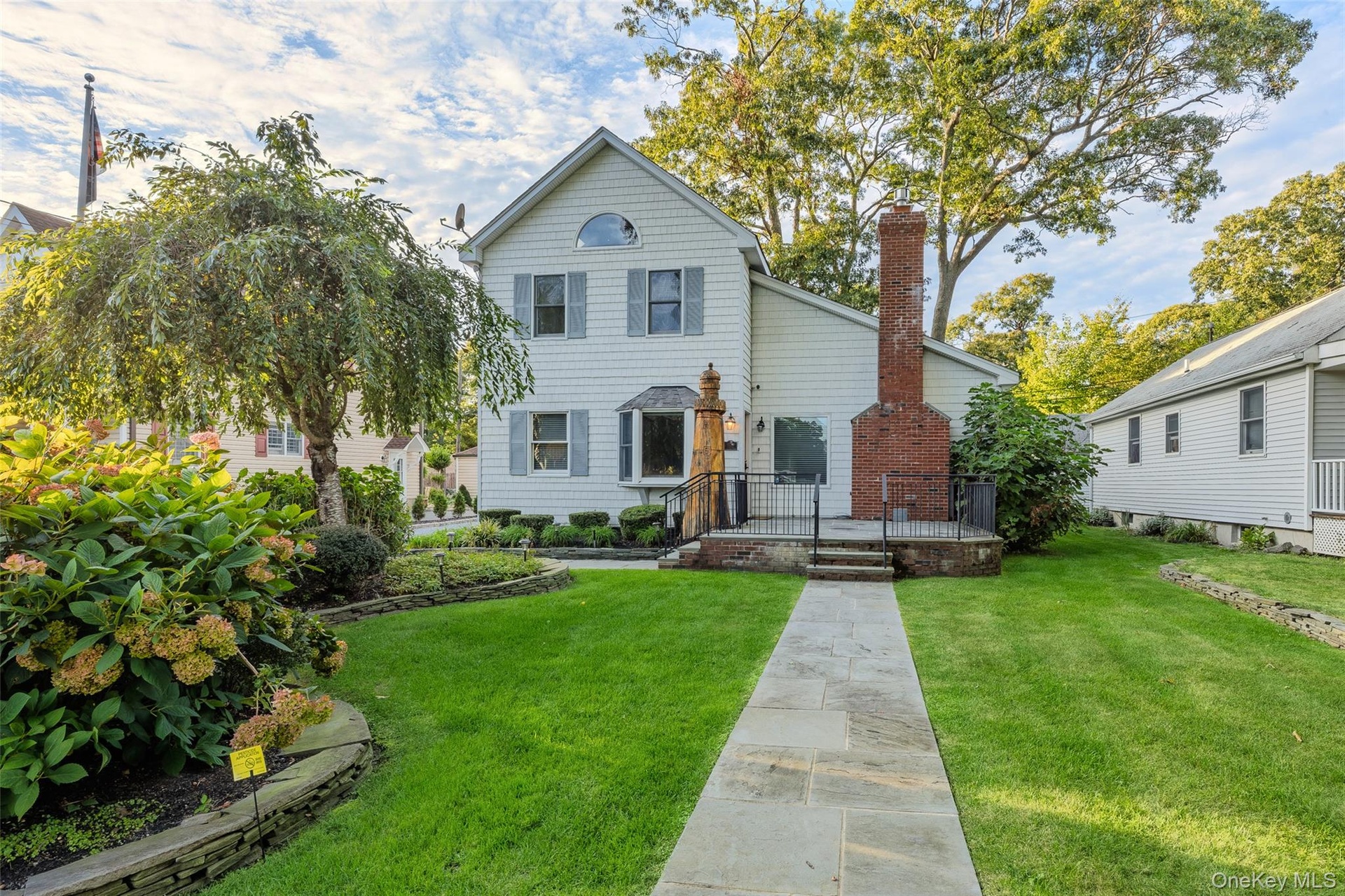 White siding exterior featuring blue shutters, a prominent brick chimney, and a stone walkway