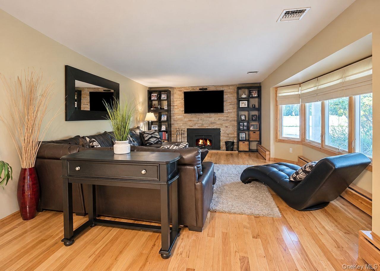 Wood-finish flooring throughout, a stone-clad fireplace, and integrated shelving fireplace with insert