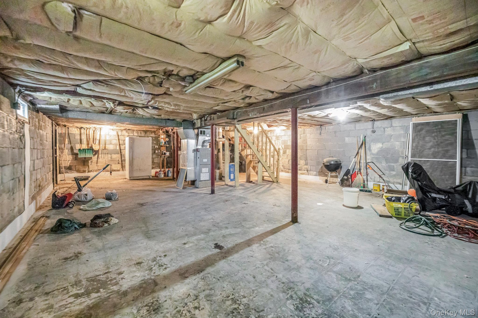 Unfinished basement featuring stairway and heating unit