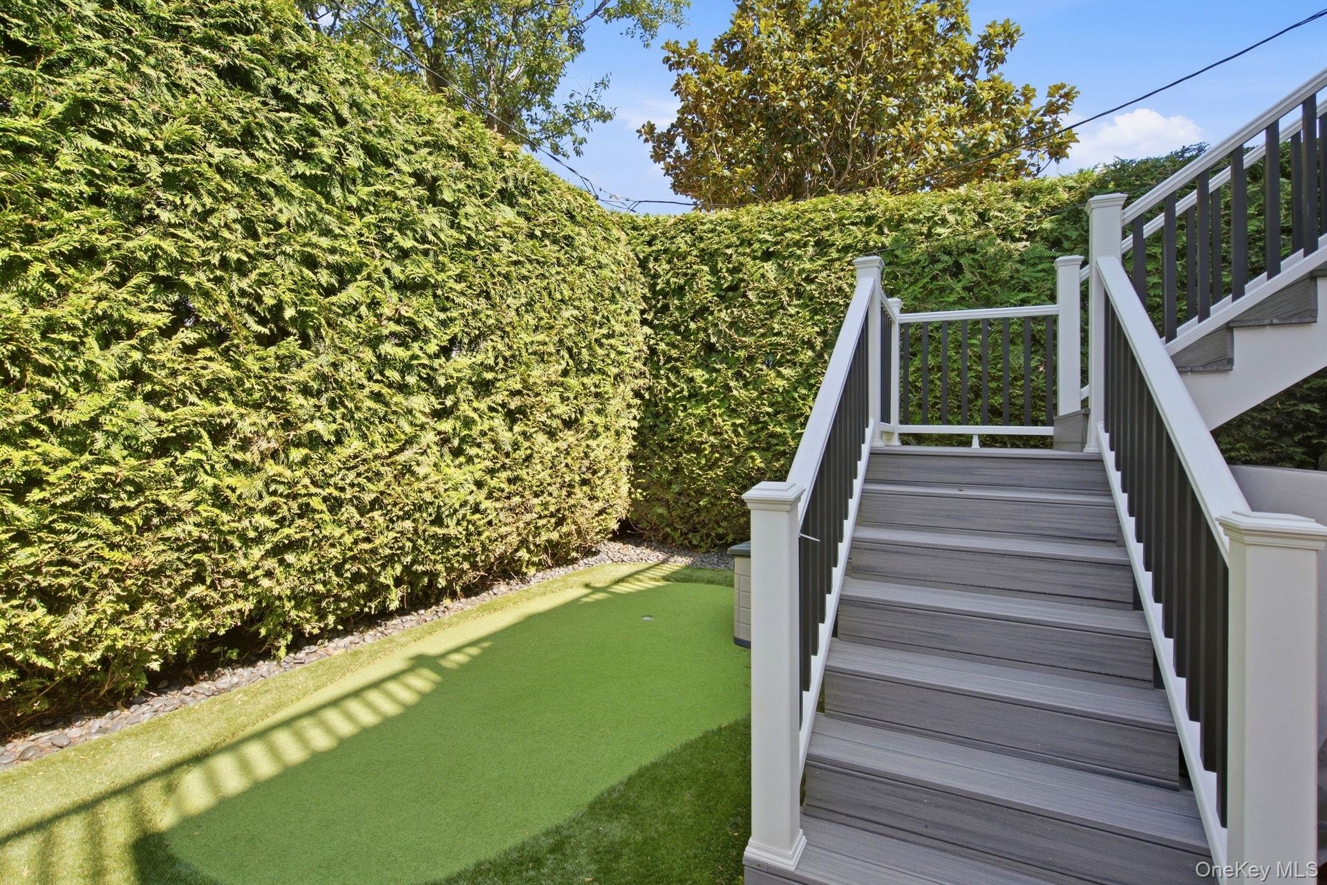 Turf lawn and putting green with stairs to primary bedroom private deck