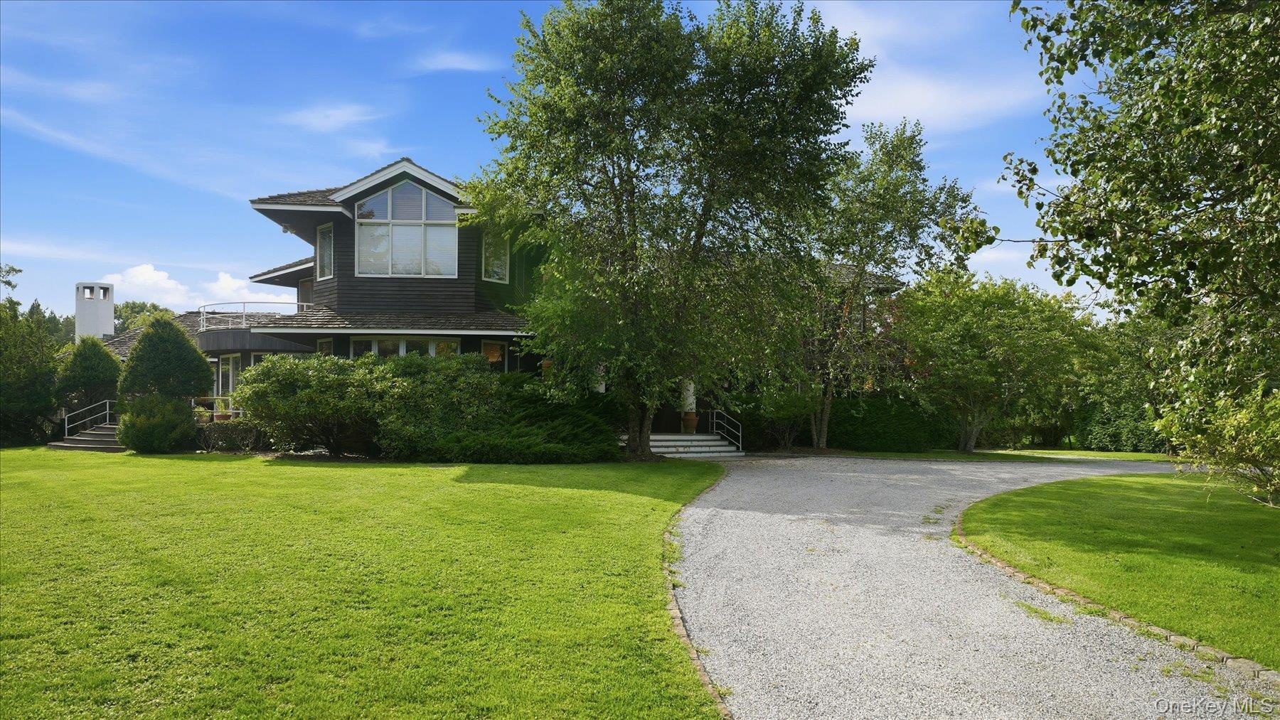 Front: long driveway with home behind row of mature landscaping