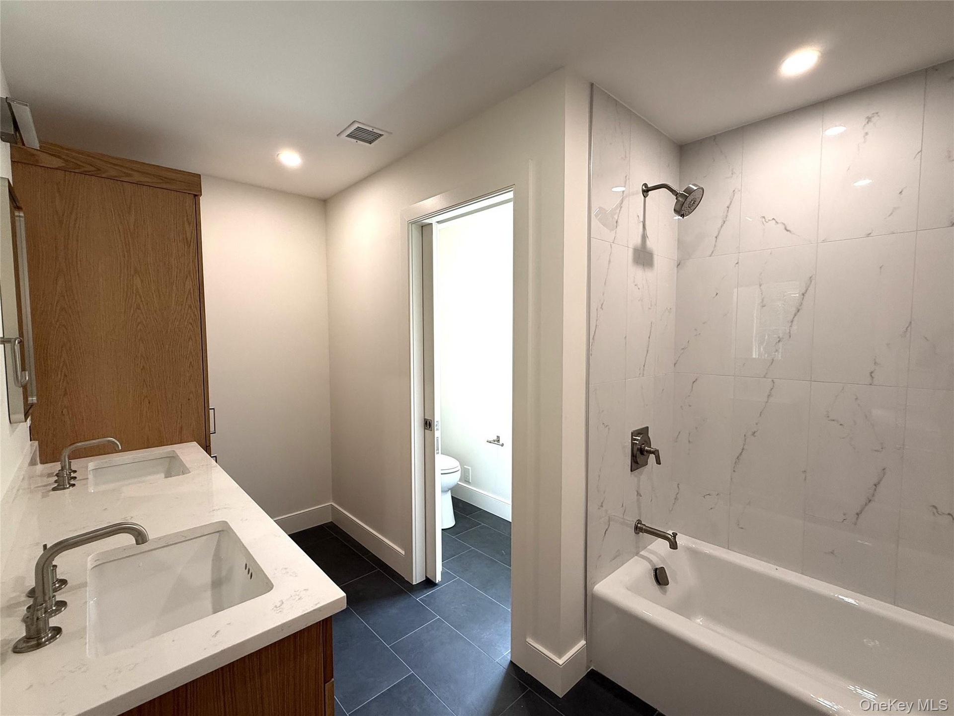 Bathroom featuring double sink vanity and bathtub with shower