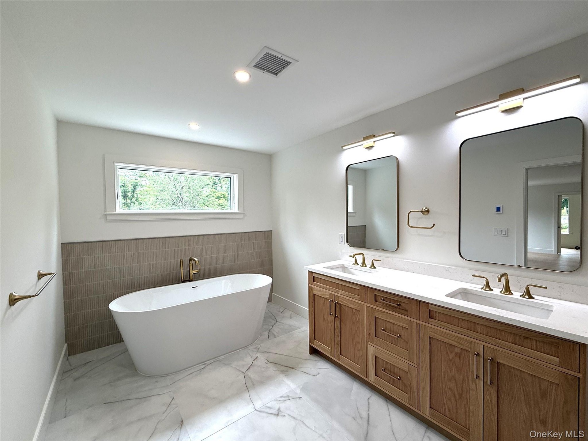 Primary Bathroom featuring a freestanding soaking tub and dual vanity with wood cabinetry