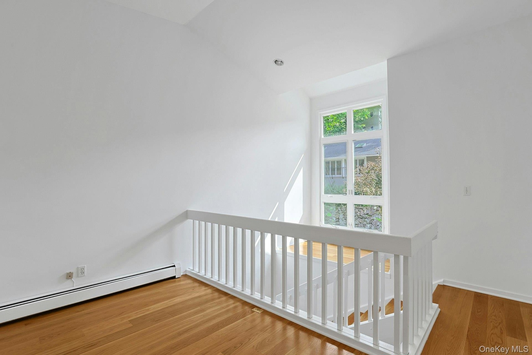 From the loft, we look over to the wall of windows that welcome in tons of natural light. There is a perfect seating area or spot for plants just in f