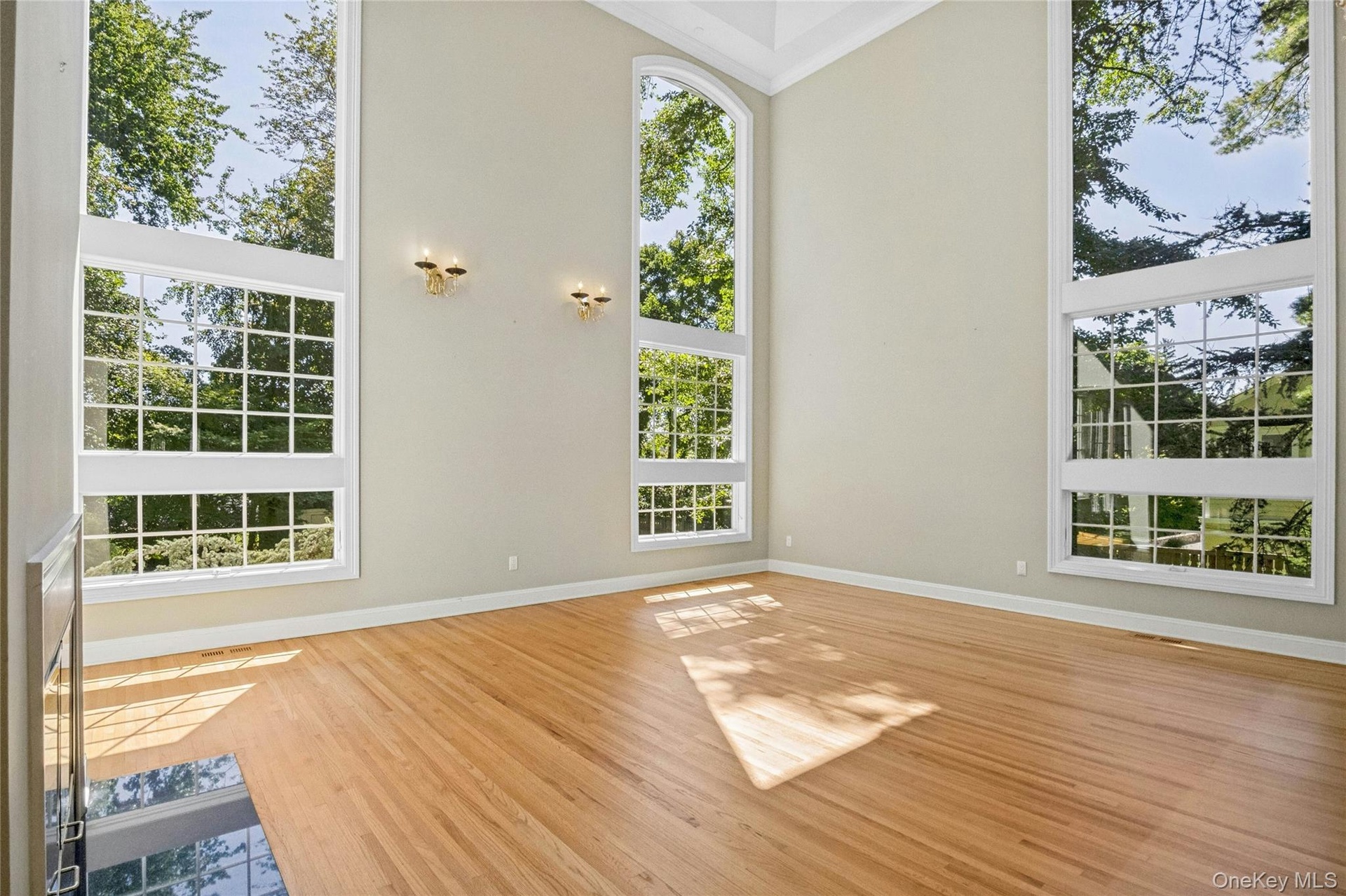 Impressive living room with high ceiling and massive windows that allow natural light and views of  property.