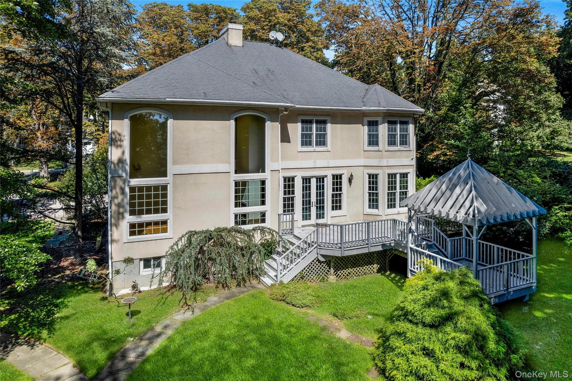 Stucco exterior with multi-pane windows, elevated deck, and a gazebo