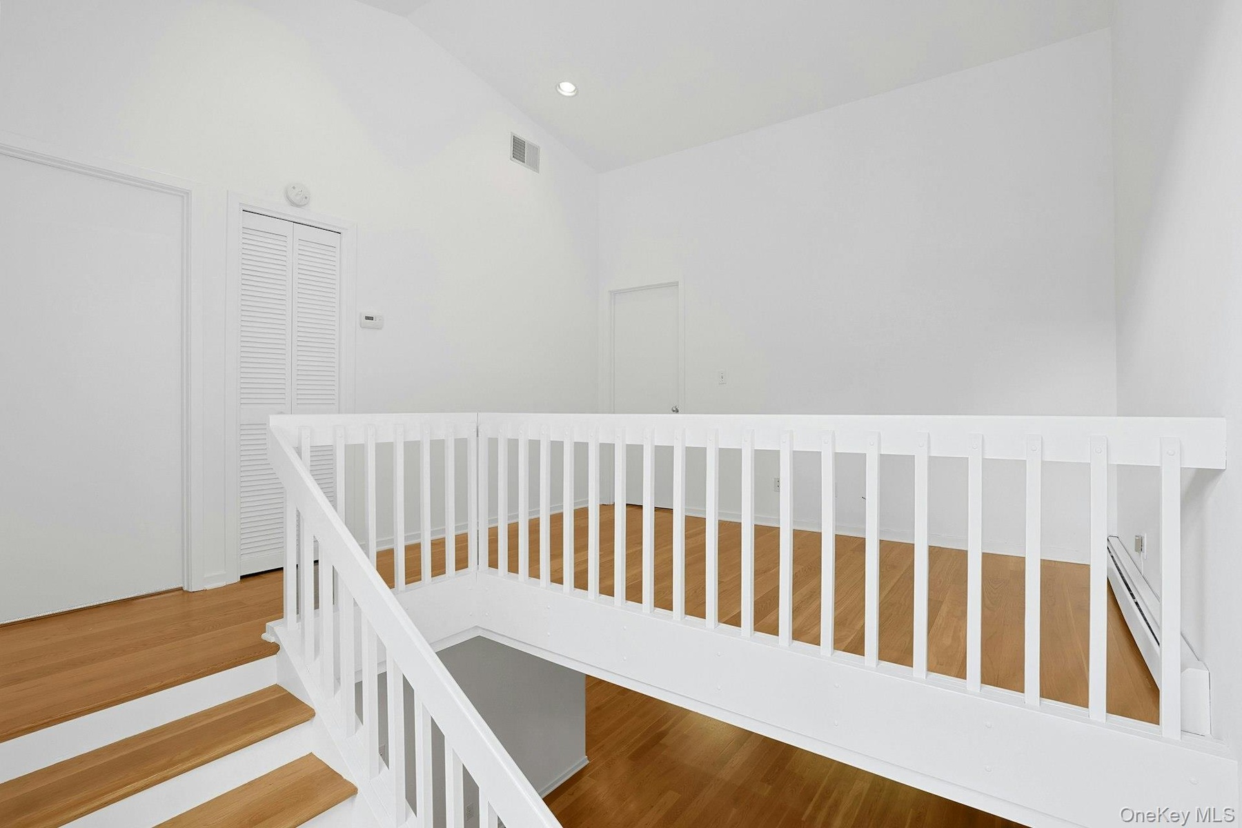 Up the beautiful staircase to the second level, we find the loft, which has a cathedral ceiling that soars to twelve feet overhead. Centrally located 