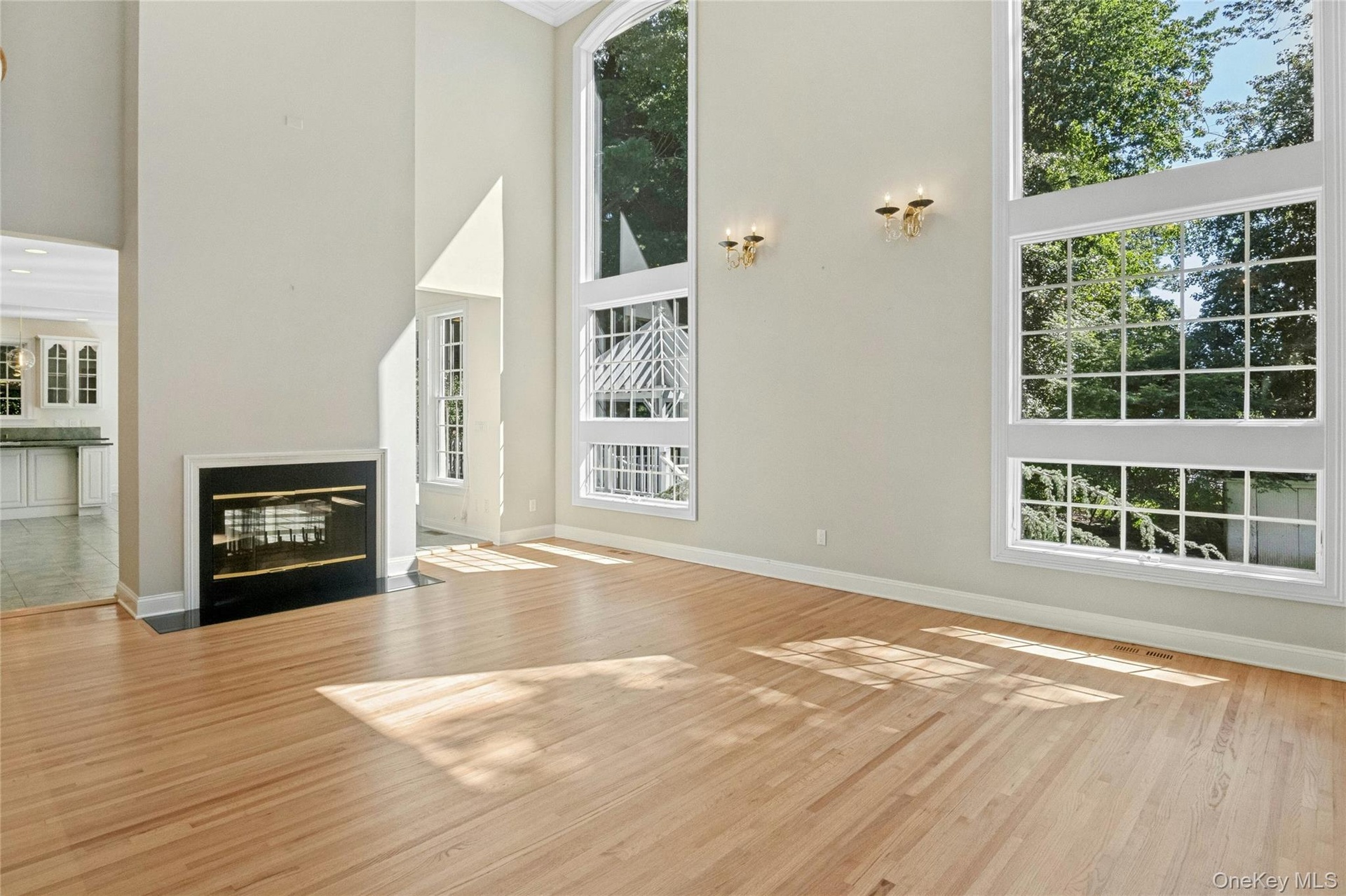 Living room with two story windows. An impressive room filled with natural light and views of the mature landscaping.