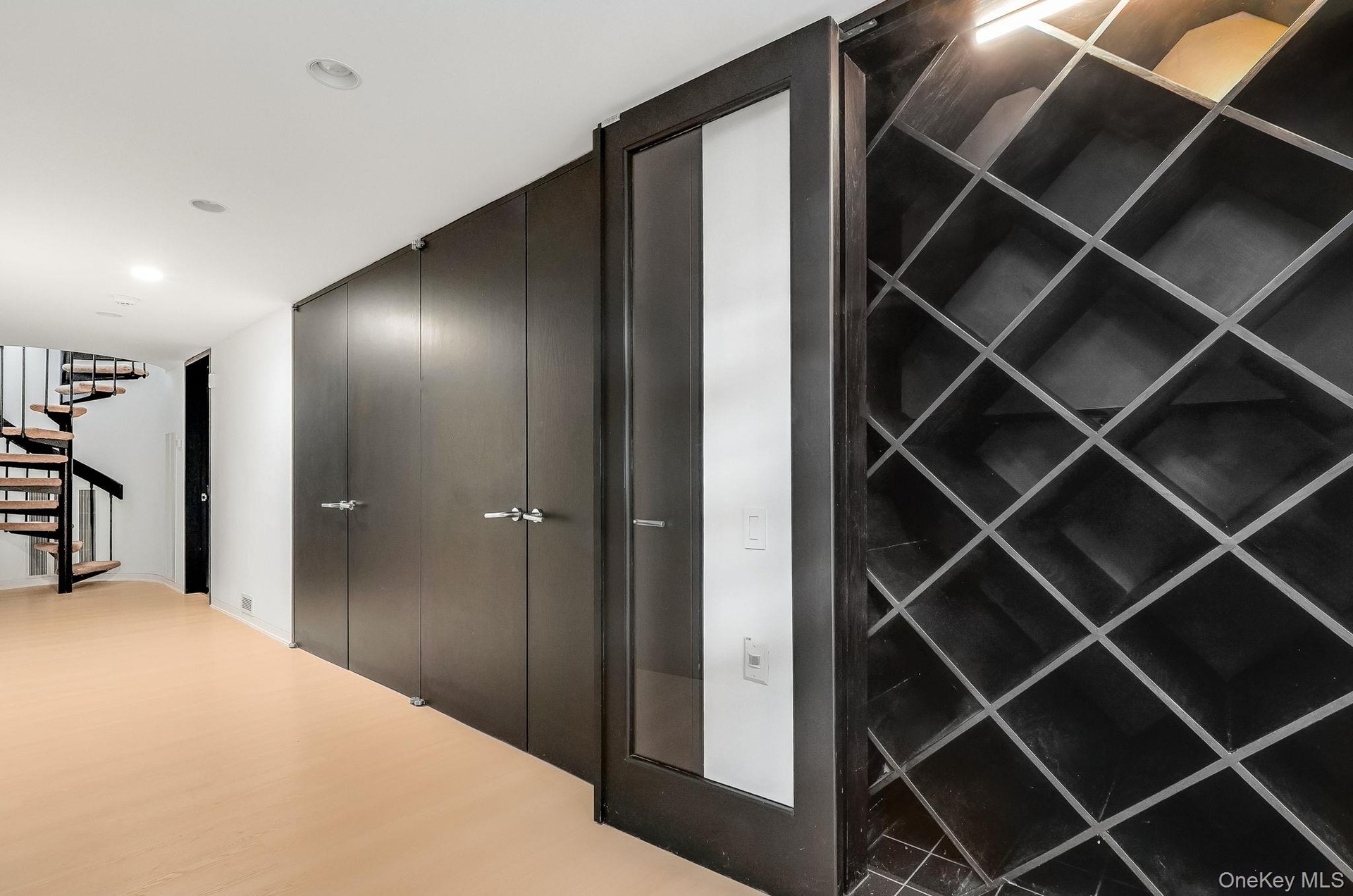 An elegant built-in wine wall featuring custom diamond-grid shelving and a modern glass-paneled accent door.
