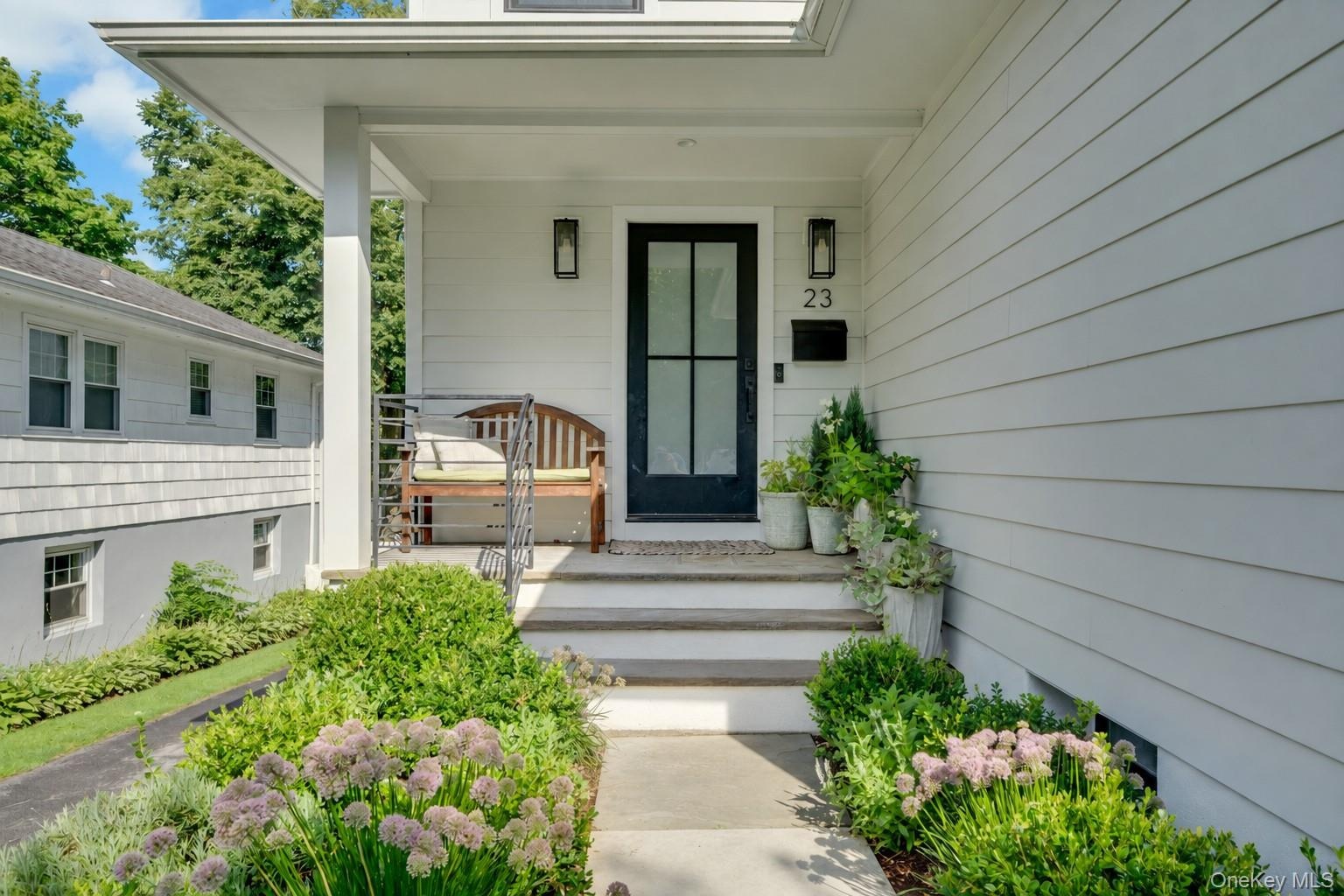 A charming covered front porch- the perfect spot for morning coffee, greeting neighbors, and taking in the beautifully landscaped surroundings.