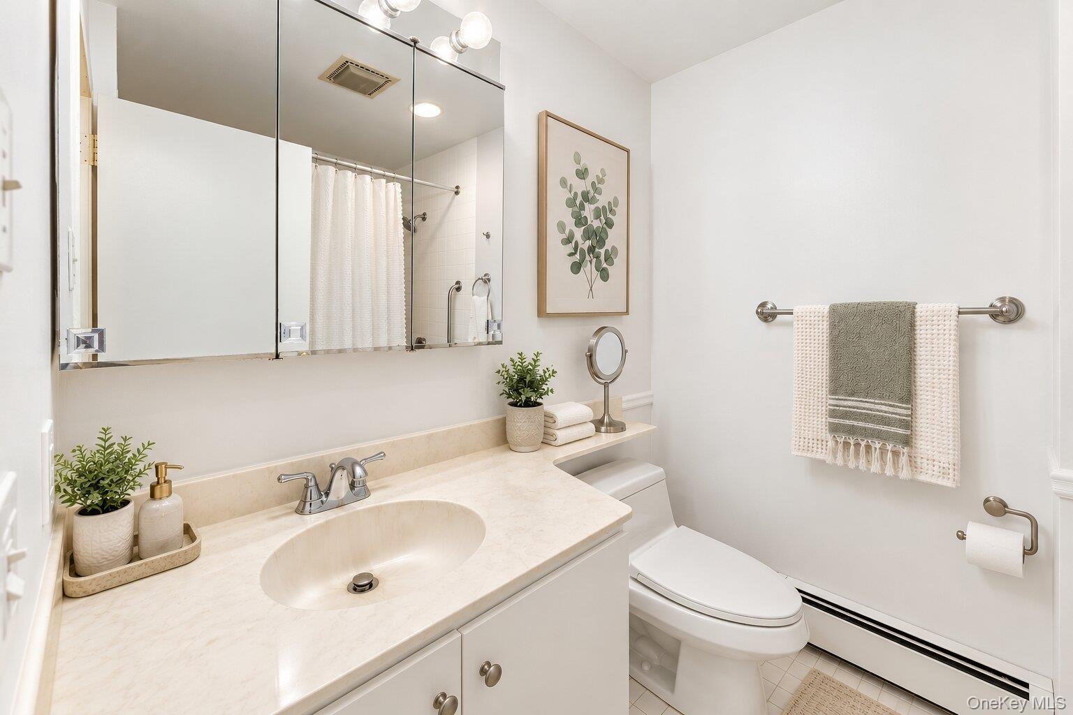 Vanity with an integrated sink and light-colored countertop, wall-mounted medicine cabinet with mirror, and a toilet with an adjacent shelf