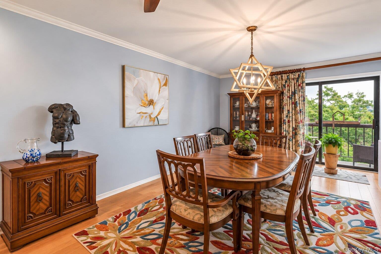 Light wood-finish flooring with crown molding and a prominent chandelier