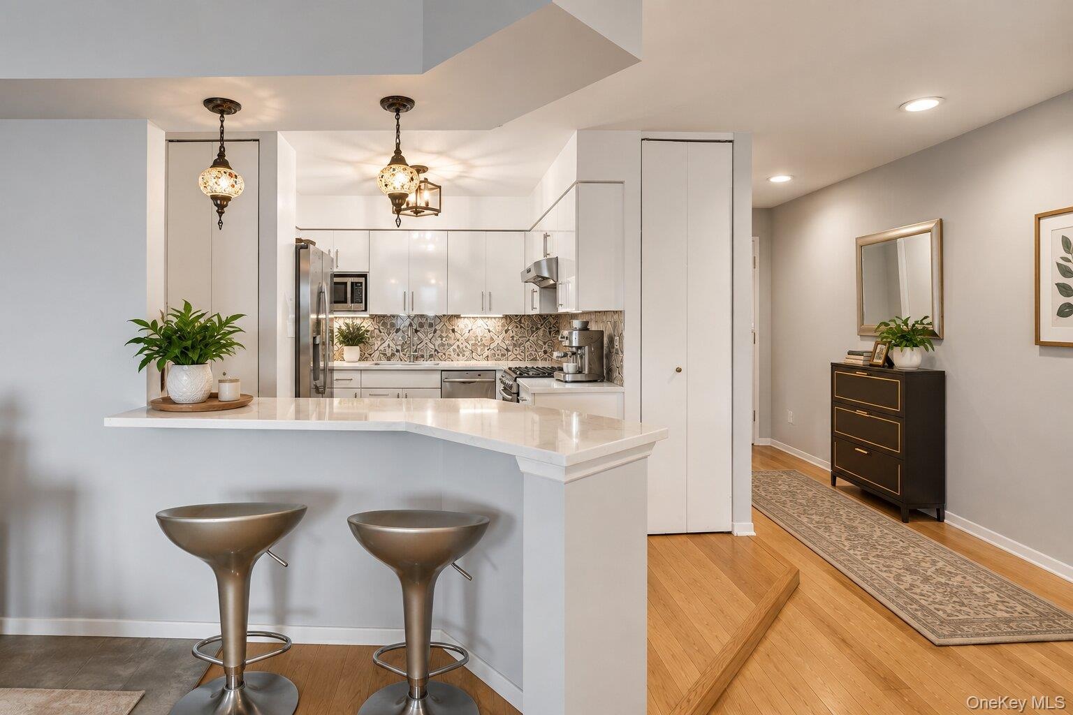 Kitchen featuring white cabinetry, stainless steel appliances, and a patterned tile backsplash