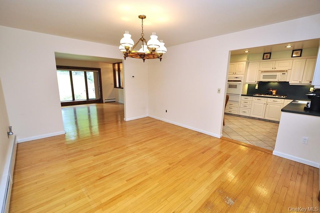 Photo Visually Staged.  The Dining Room has hardwood floors, opens to both the Kitchen and Living room and has sliding glass doors to the back patio a